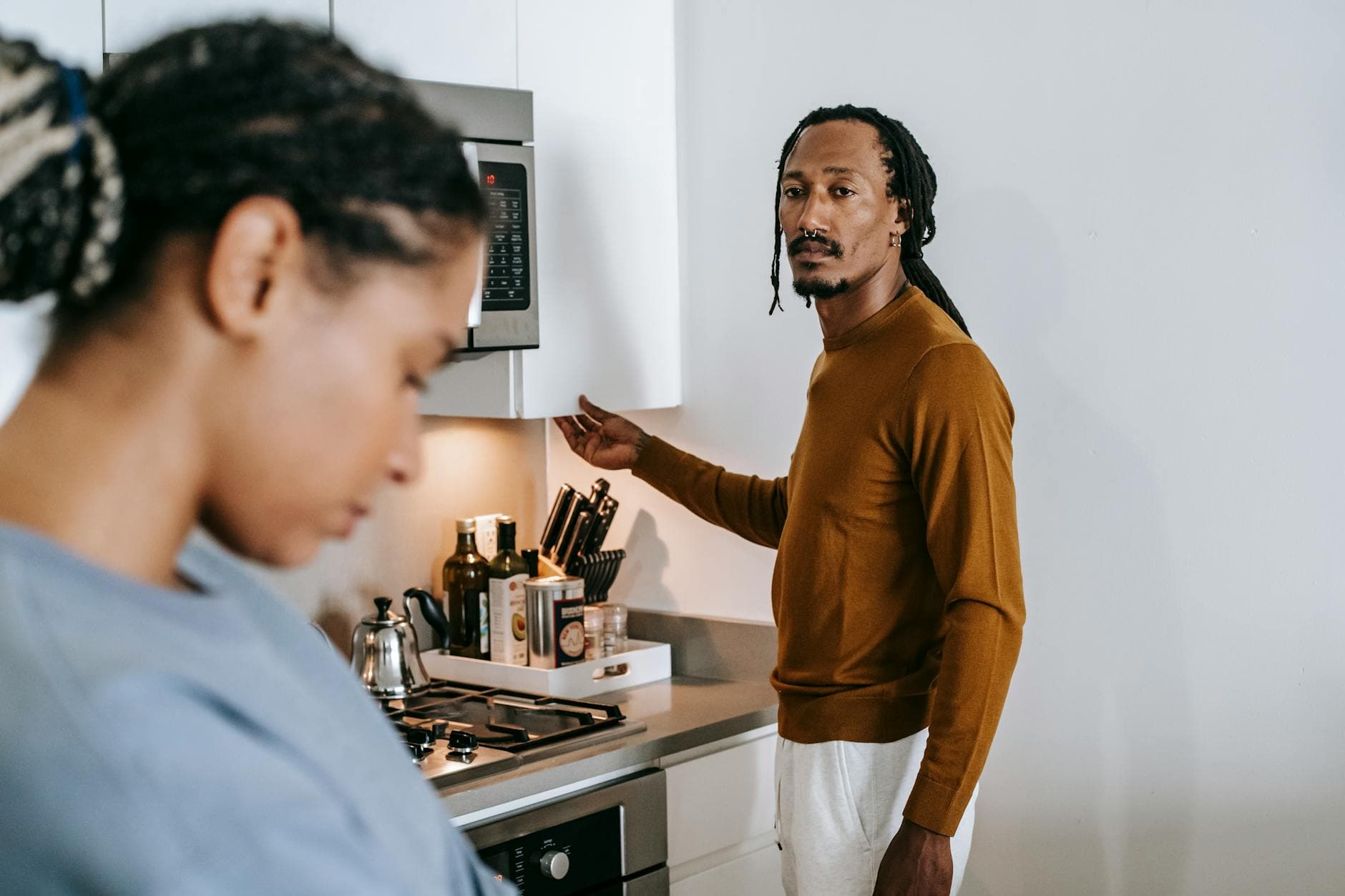 A young couple in their kitchen, visibly upset and in a tense discussion. - conflict resolution definition