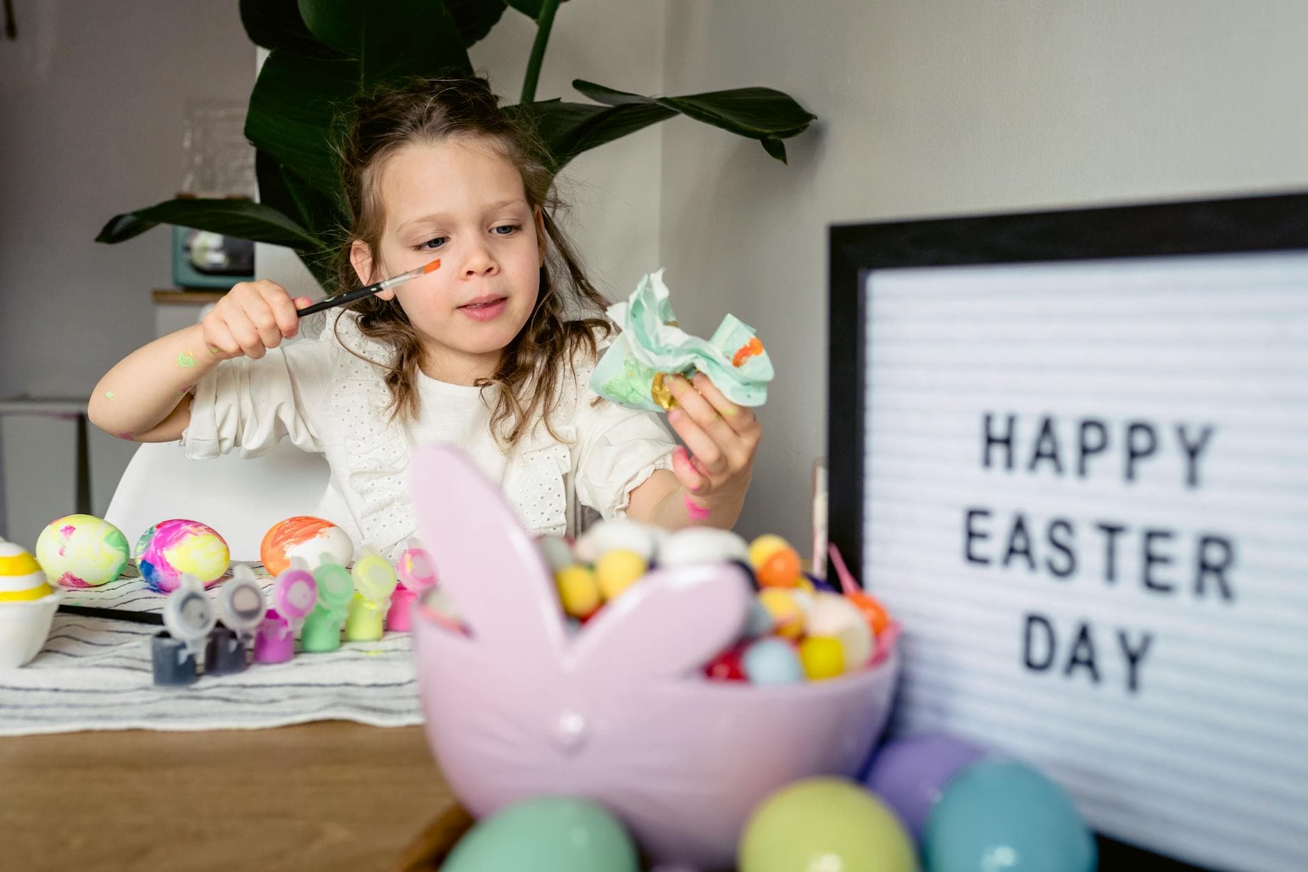 Child painting Easter eggs with creativity and joy indoors, embracing festive traditions. - preparing kids for spring transition