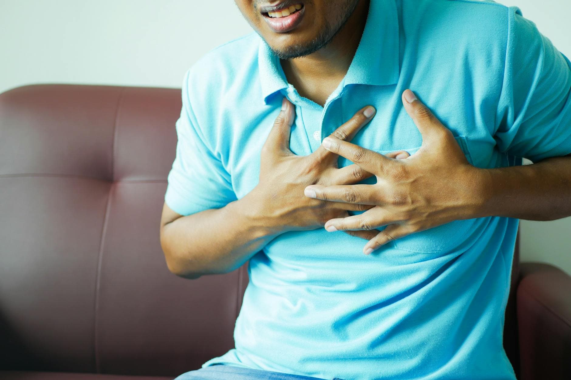 A close-up image of a man clutching his chest, indicating heart pain or discomfort. - relationship anxiety symptoms