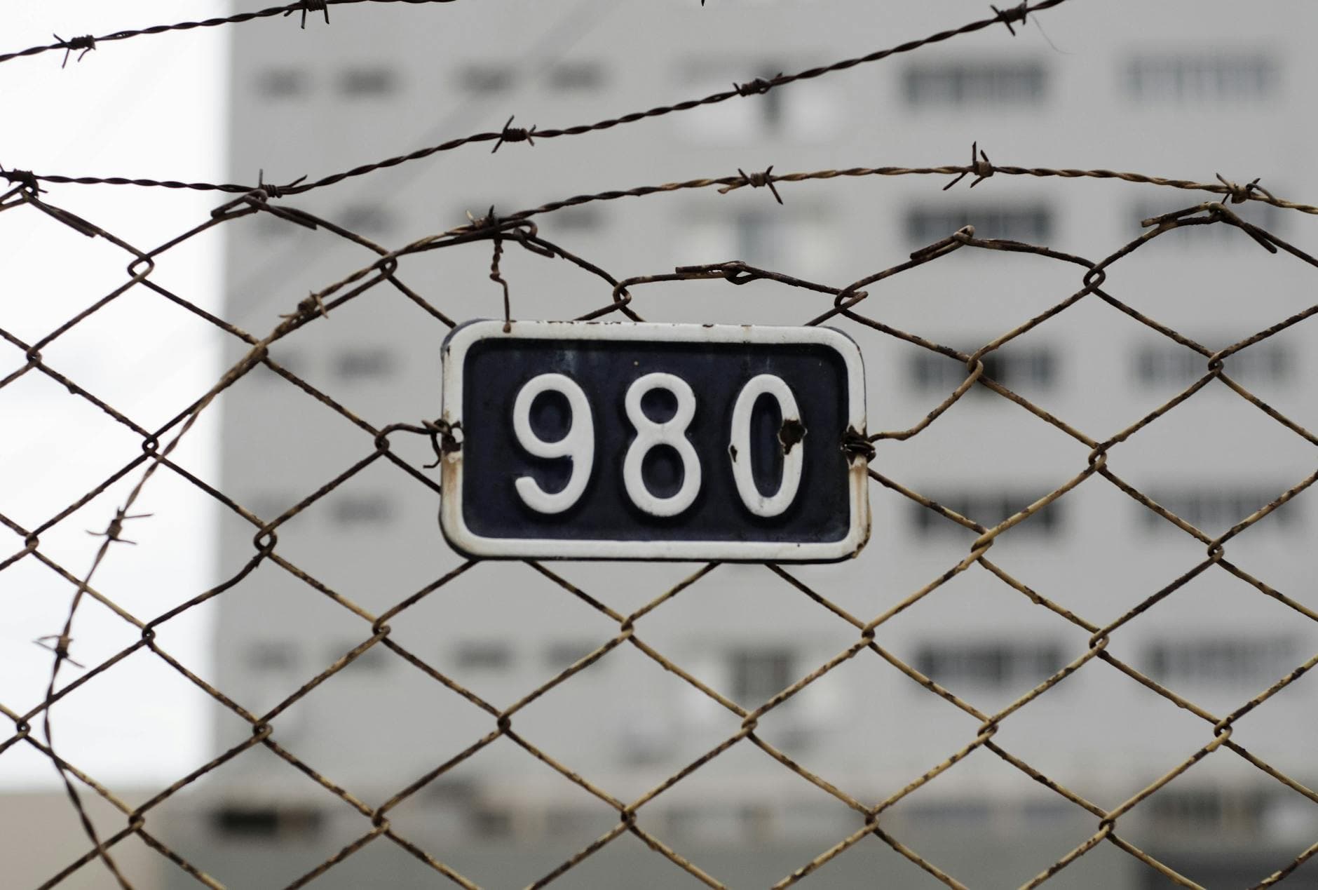 Close-up of a barbed wire fence with a metal number plate. Symbolizes security and restriction. - setting boundaries holidays