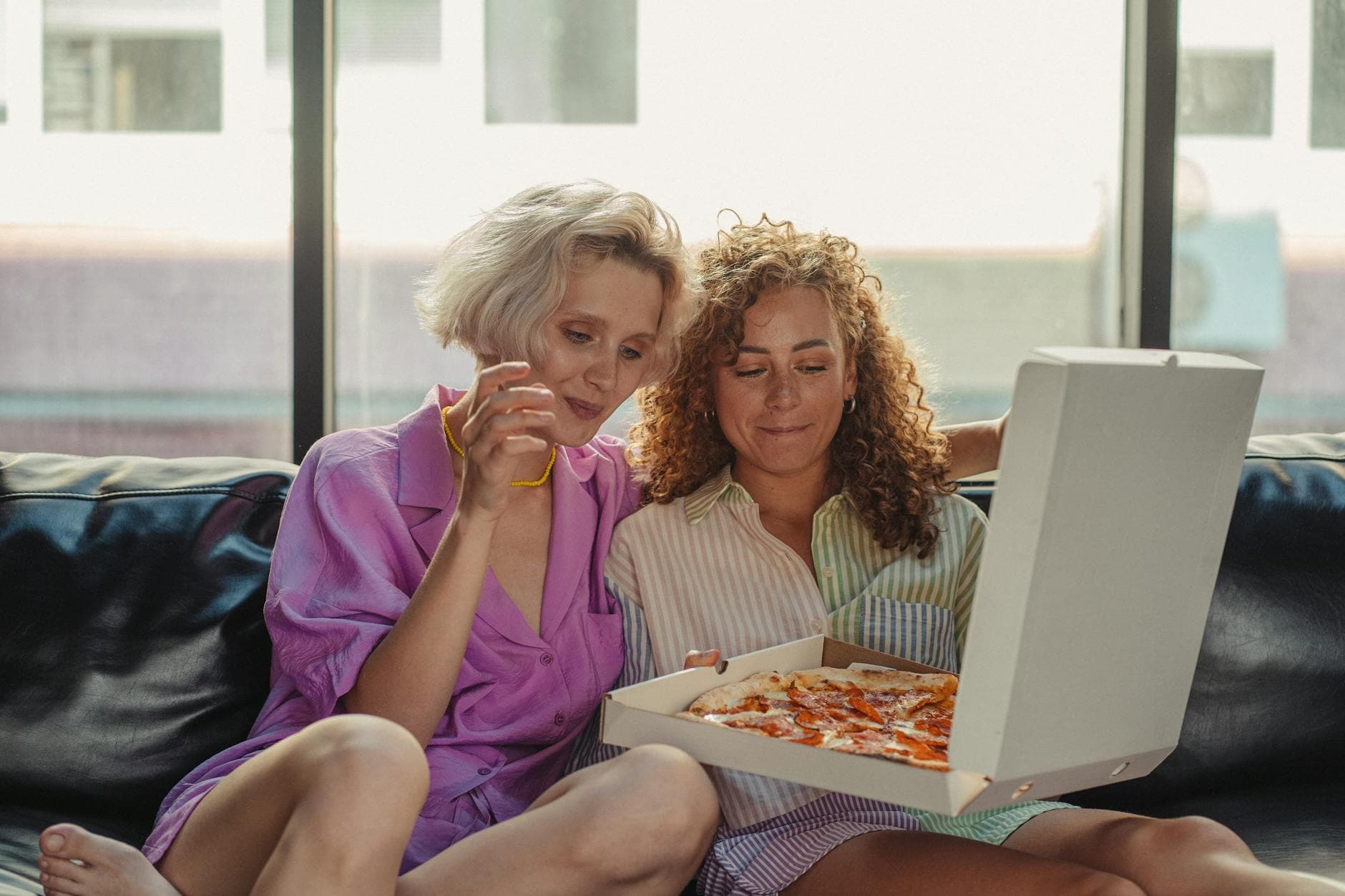 A loving couple sharing pizza while relaxing together at home indoors. - shared relationship goals