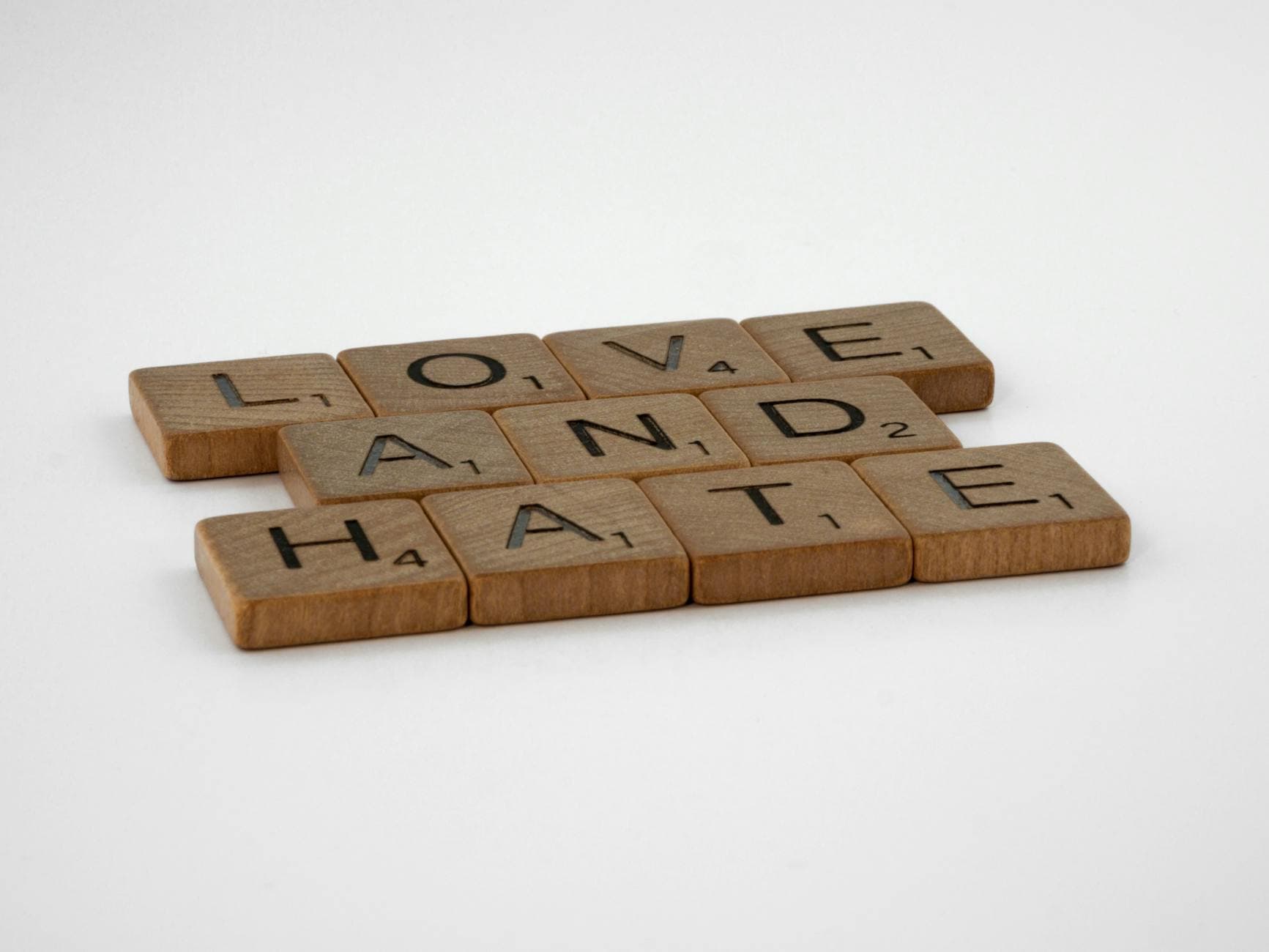 Close-up of Scrabble tiles spelling 'Love and Hate' on a white background, symbolizing complex emotions. - winter love languages ideas