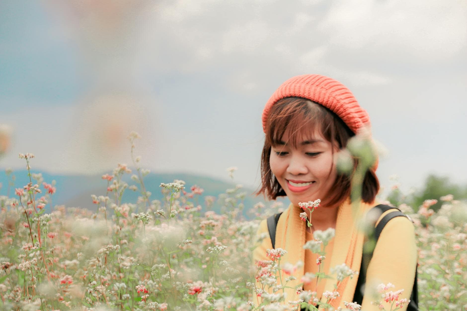 A joyful adult woman with a beanie enjoys blooming flowers in a vibrant garden. - allergy mood changes