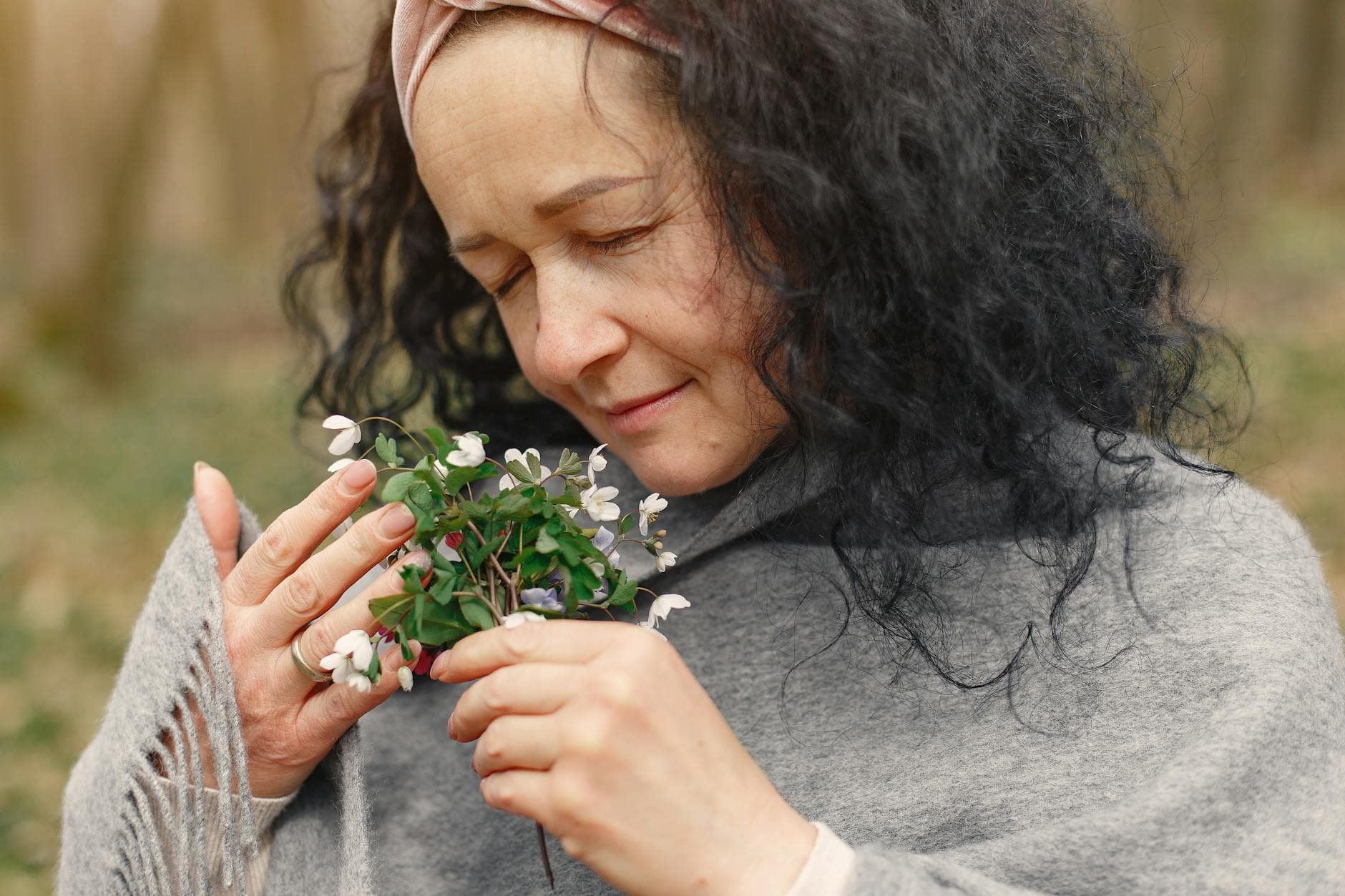 Portrait of a woman enjoying the aroma of spring flowers outdoors. - allergy mood therapy