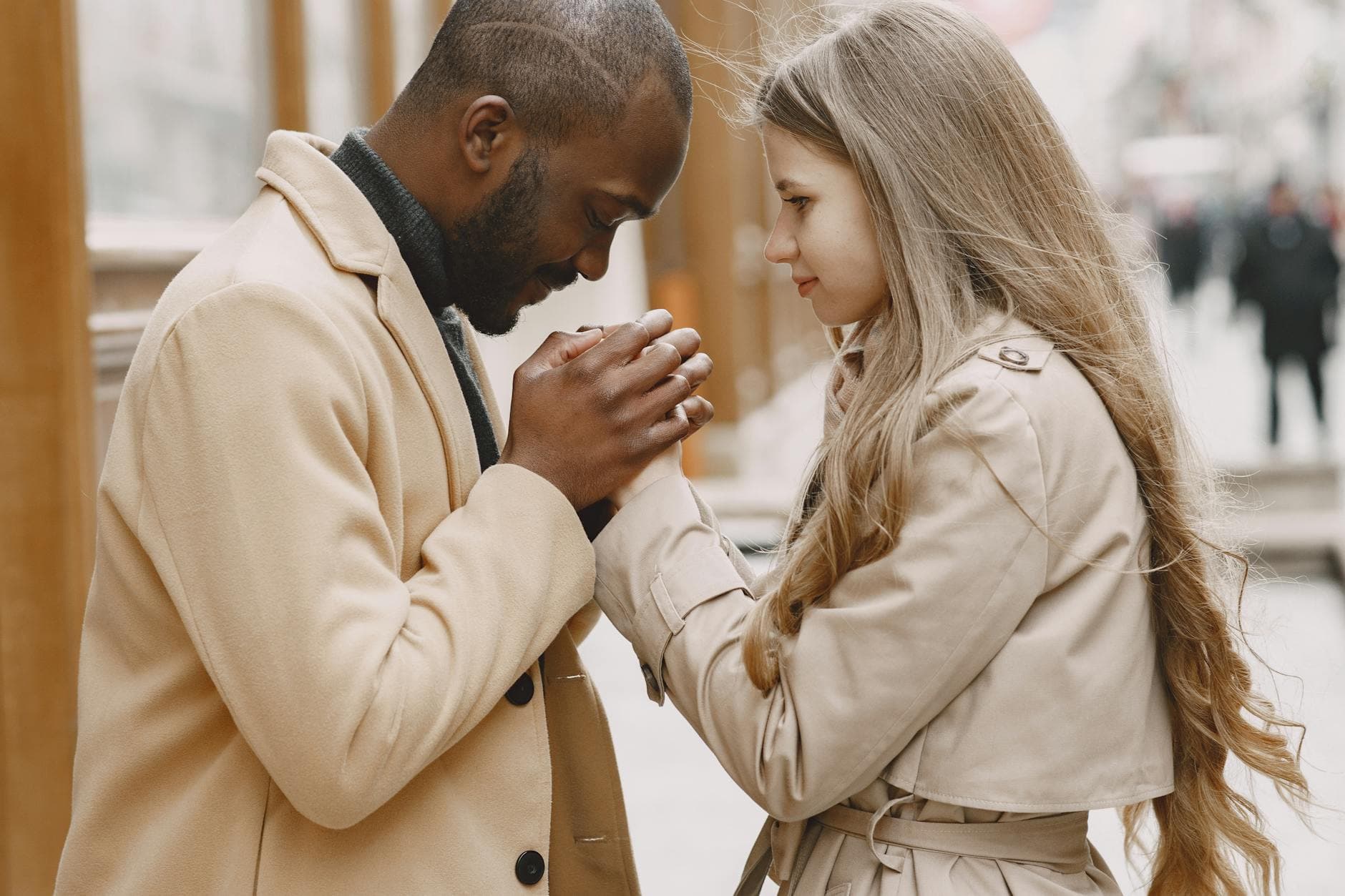 A multiracial couple in winter clothing sharing an intimate moment outdoors. - apologize to a man