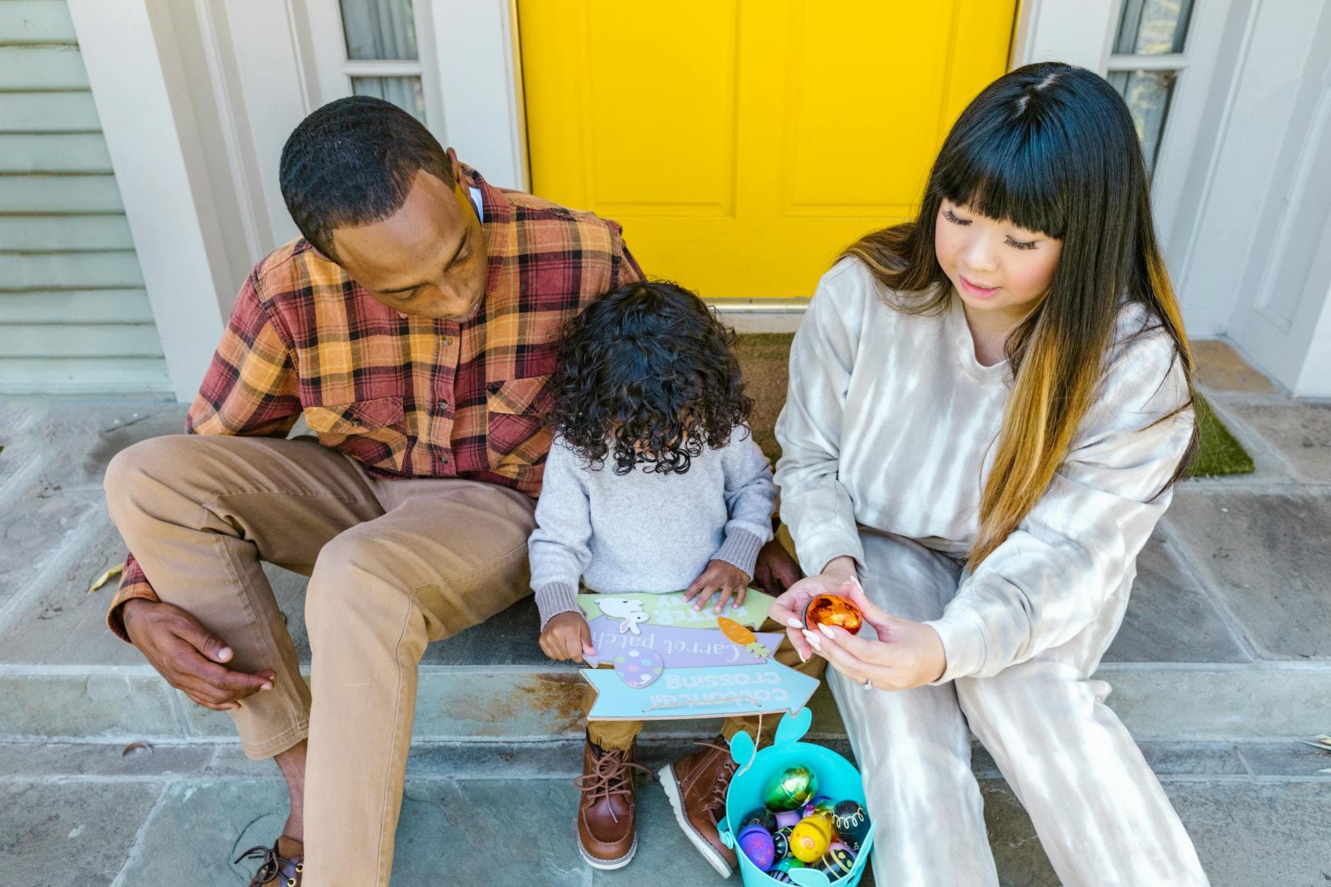 A multiracial family enjoying Easter activities on their front porch. - co-parenting spring break