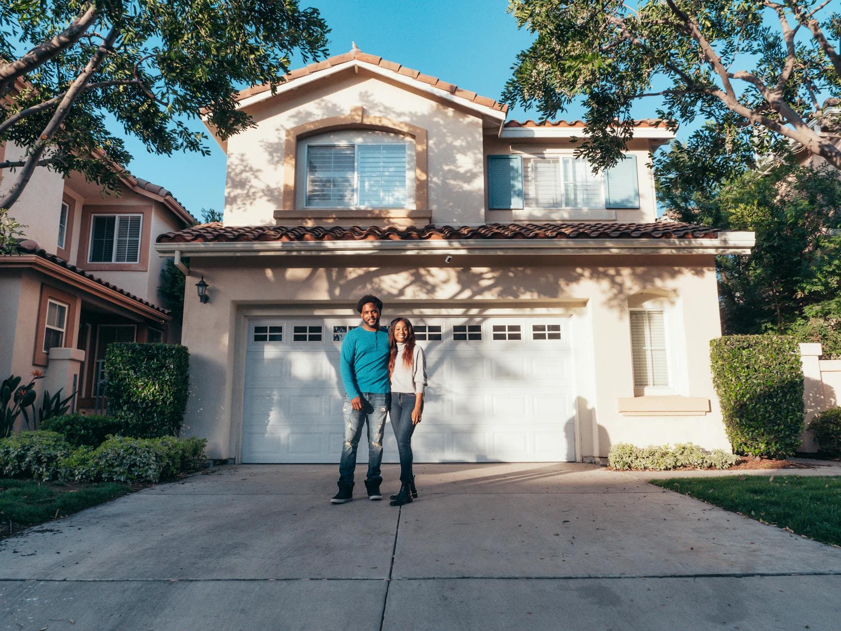 Smiling couple standing outside their newly purchased house on a sunny day. - couple communication goals