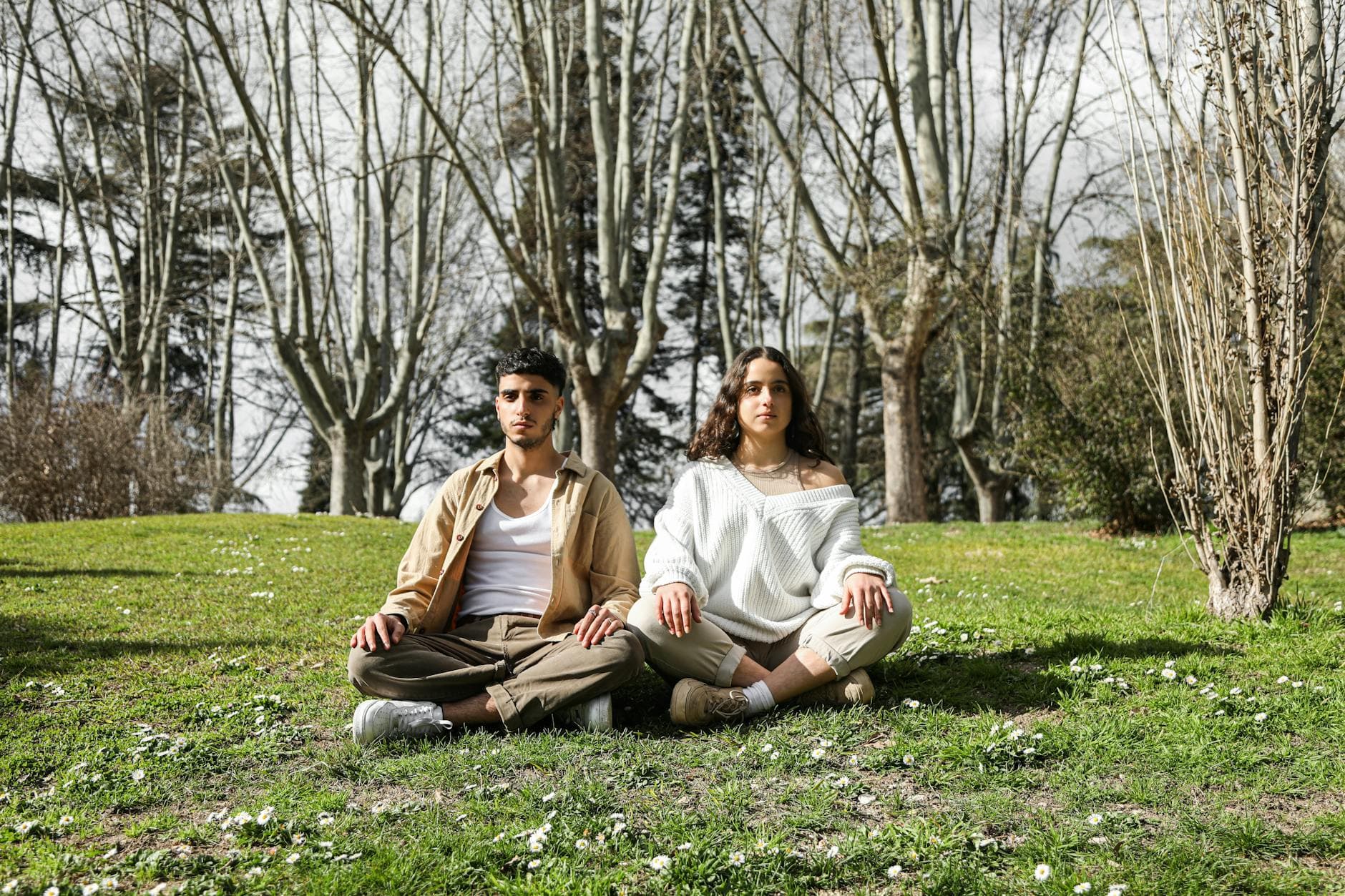 A peaceful couple practicing meditation in a tranquil park surrounded by nature. - couple resentment spring