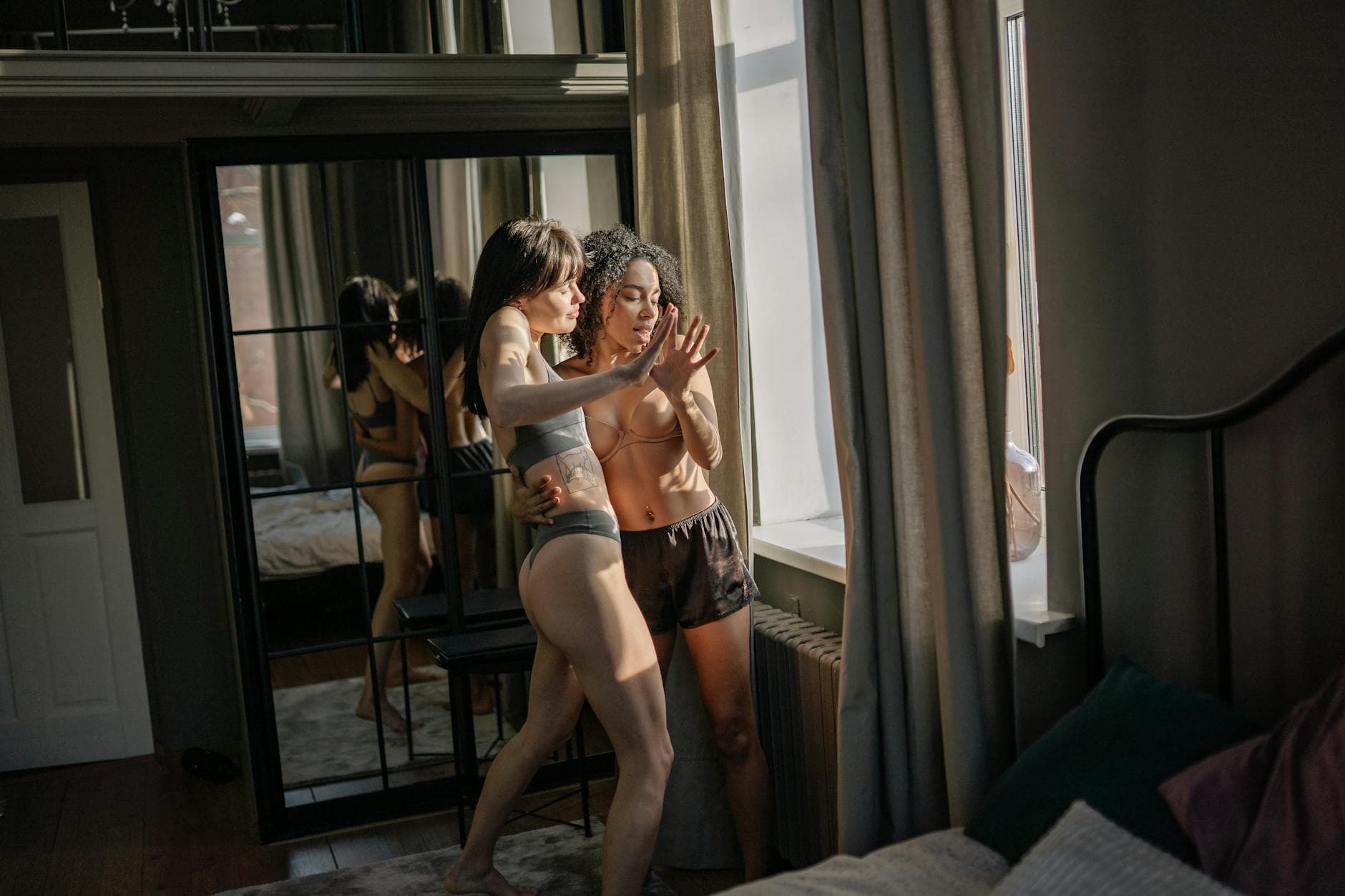 A young couple enjoying a tender moment indoors by a window, lit by soft sunlight. - couples therapy february