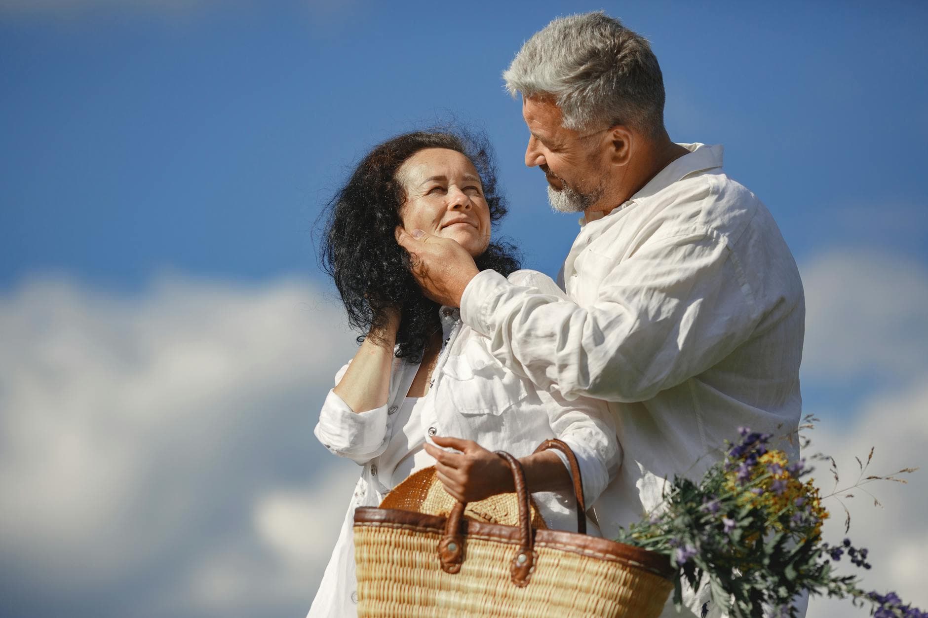 Elderly couple in love enjoying a romantic moment outdoors with a wicker basket and flowers. - empty nest symptoms