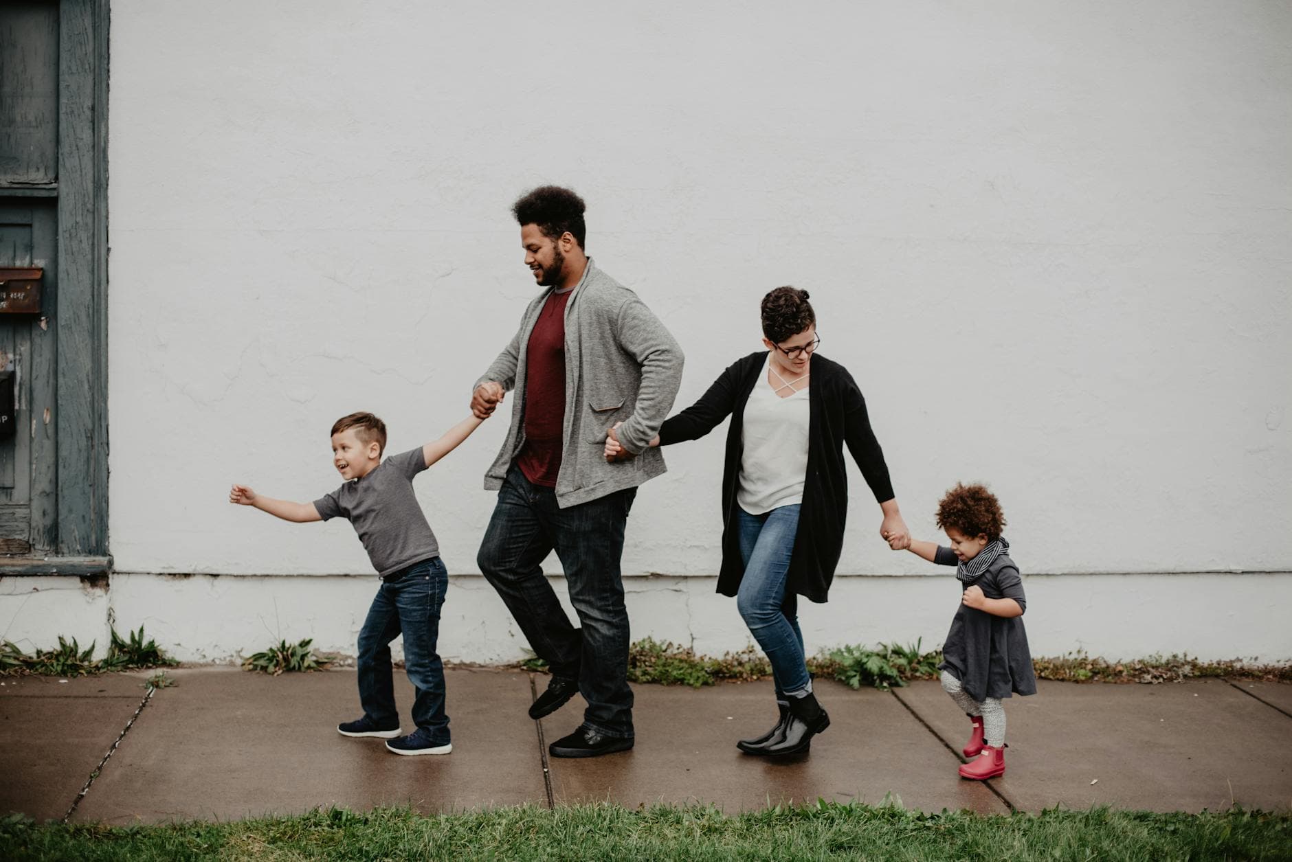 A joyful family walking together outdoors, holding hands in a playful and happy moment. - family routines with kids