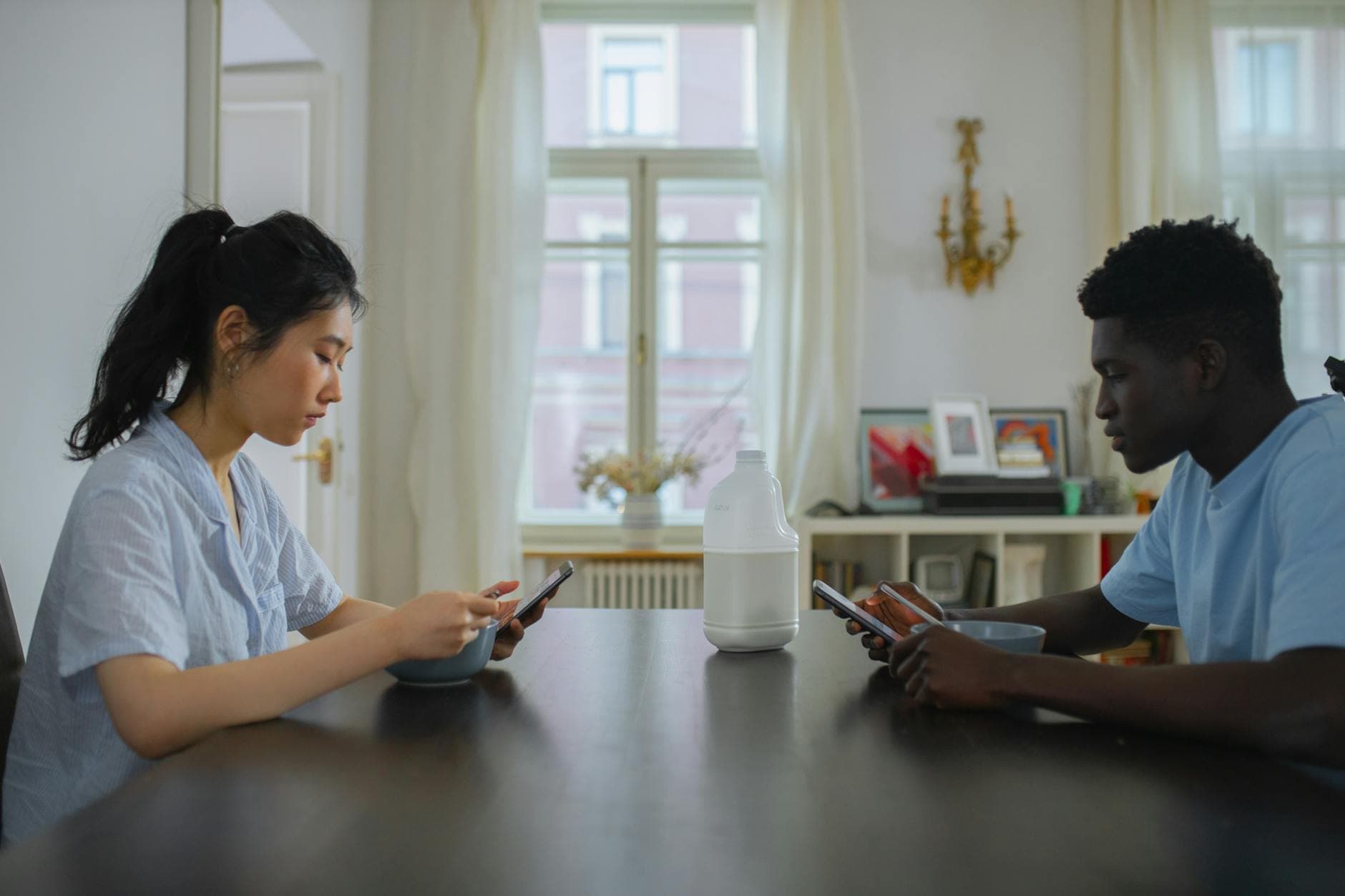 A couple engaging with their phones over breakfast, highlighting modern technology use in everyday life. - post-hibernation conversations