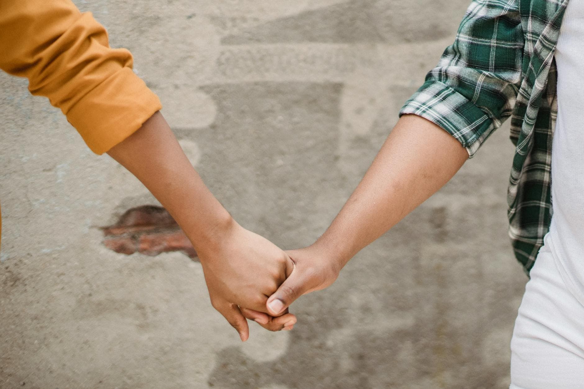 Close-up image of a couple holding hands against a textured wall, symbolizing connection. - rekindle relationship connection