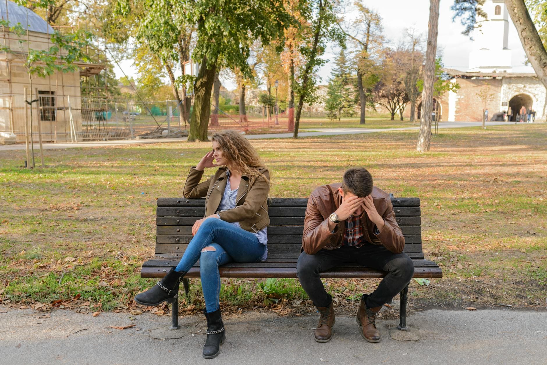 An upset couple seated on a park bench, expressing frustration during an autumn day. - relationship anxiety ocd
