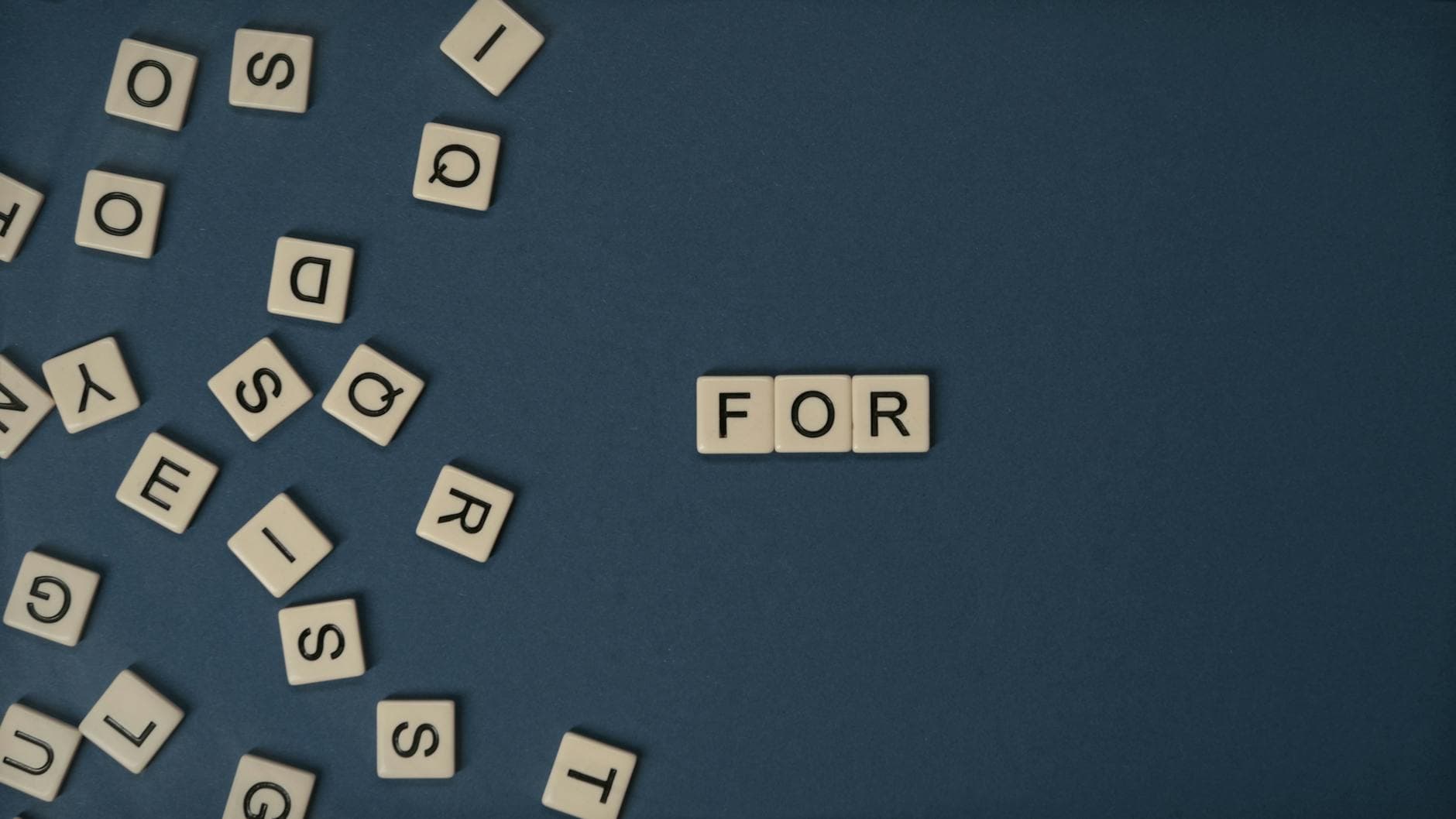 Alphabet tiles scattered on blue surface spelling the word 'FOR' with ample copy space for text. - how to spell apologize