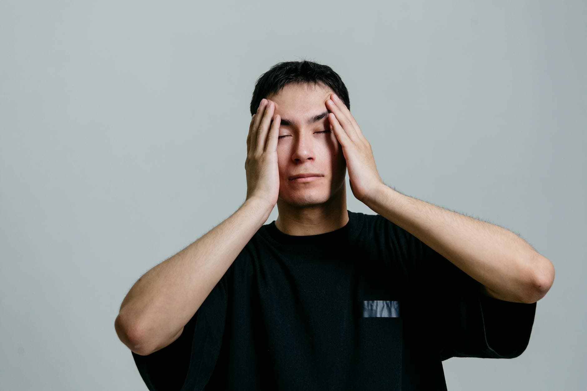 Man experiencing stress, hands on head, isolated on a gray background. - spring anxiety relief