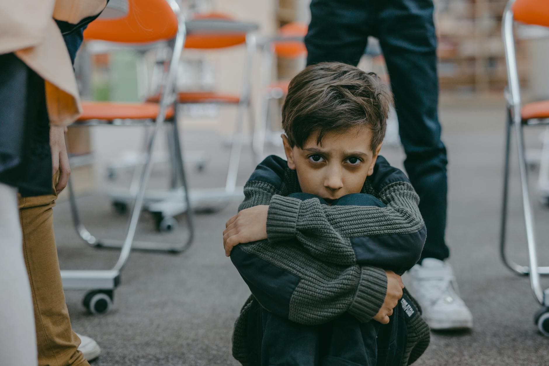 A young boy sits on the floor of a classroom, expressing fear and vulnerability. - spring social anxiety