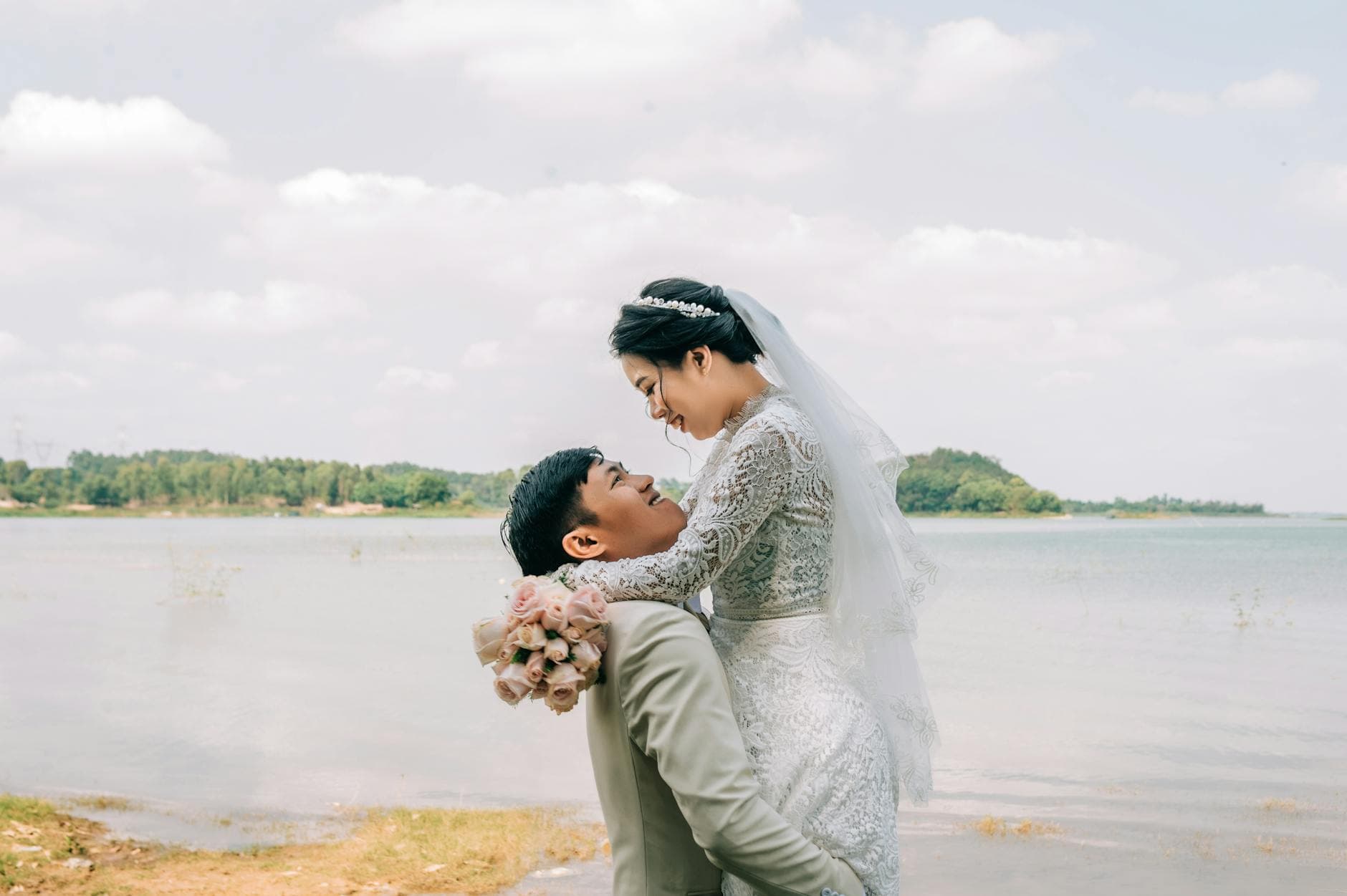 Happy bride and groom embracing by the lake on a beautiful sunny day. - expressing needs marriage