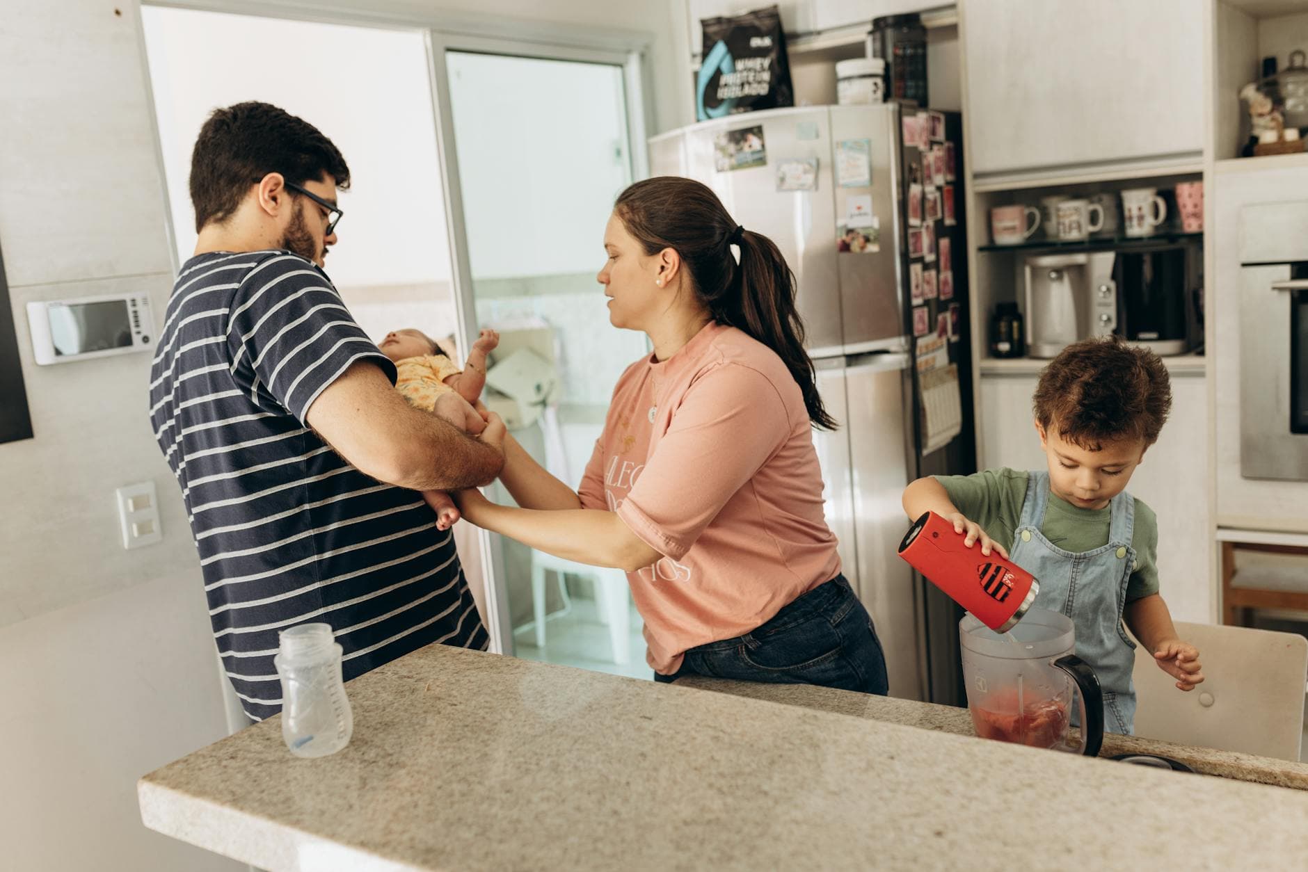 Family in a kitchen with parents and children engaged in daily activities together. - new parent exhaustion
