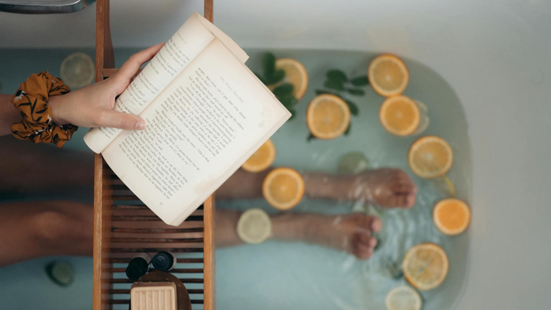 Person enjoying a citrus bath while reading a book, epitomizing relaxation. - self care habits