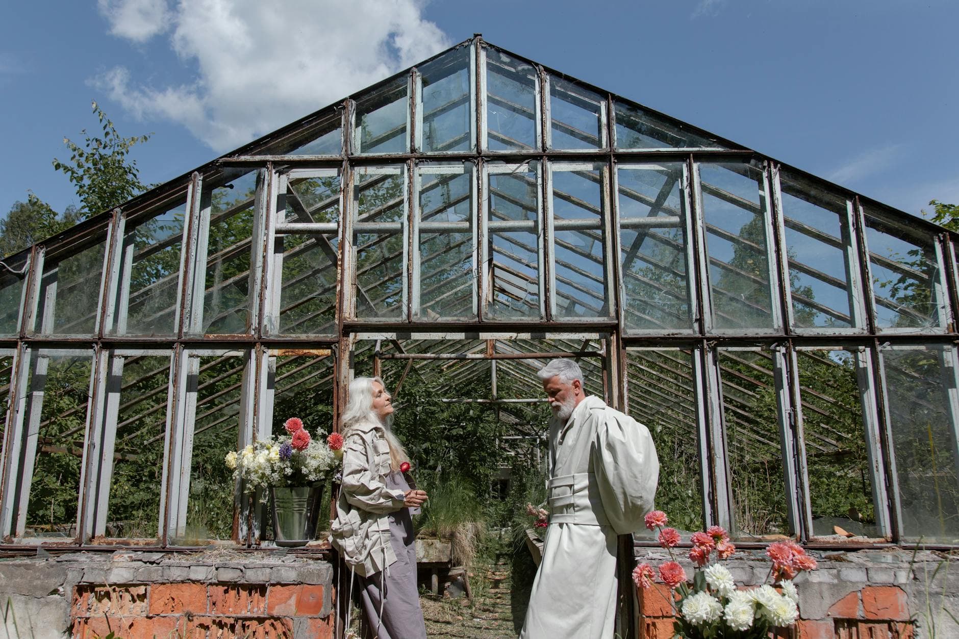 Senior couple gardening in an old greenhouse, surrounded by flowers and nature. - spring sad couples