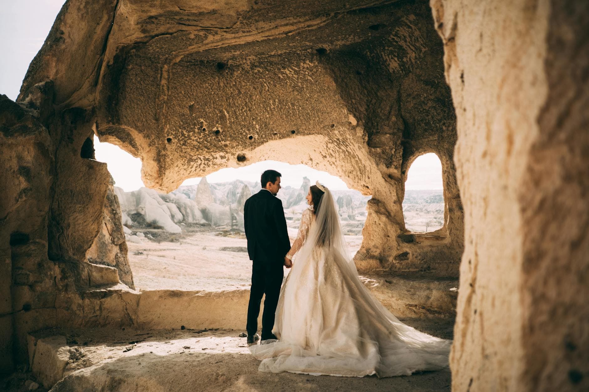Bride and groom holding hands in a stunning rock cave location, perfect for wedding memories. - marriage plateau