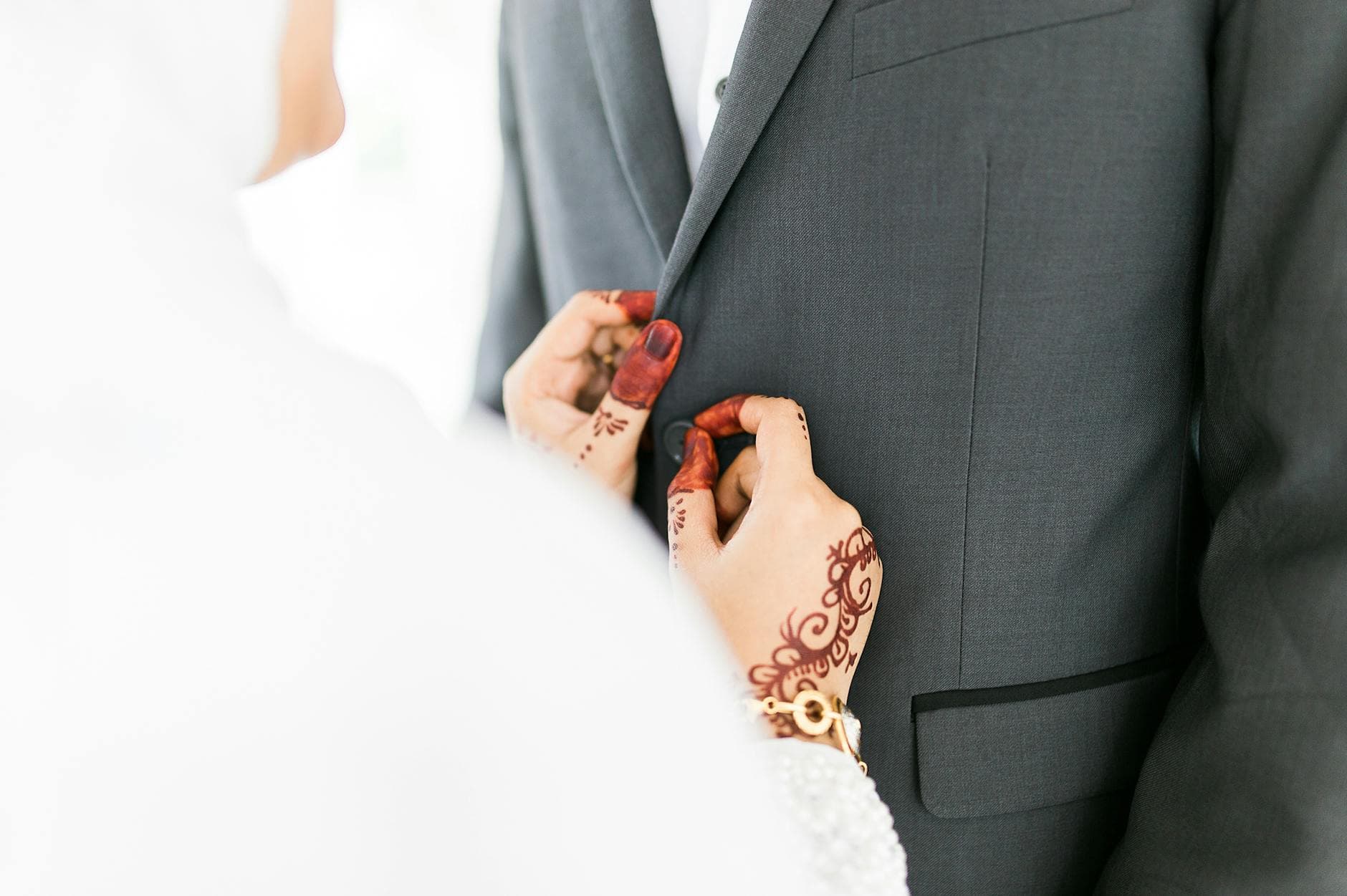 Close-up of hands adjusting groom's suit, showcasing elegant wedding attire and togetherness. - new marriage adjustments