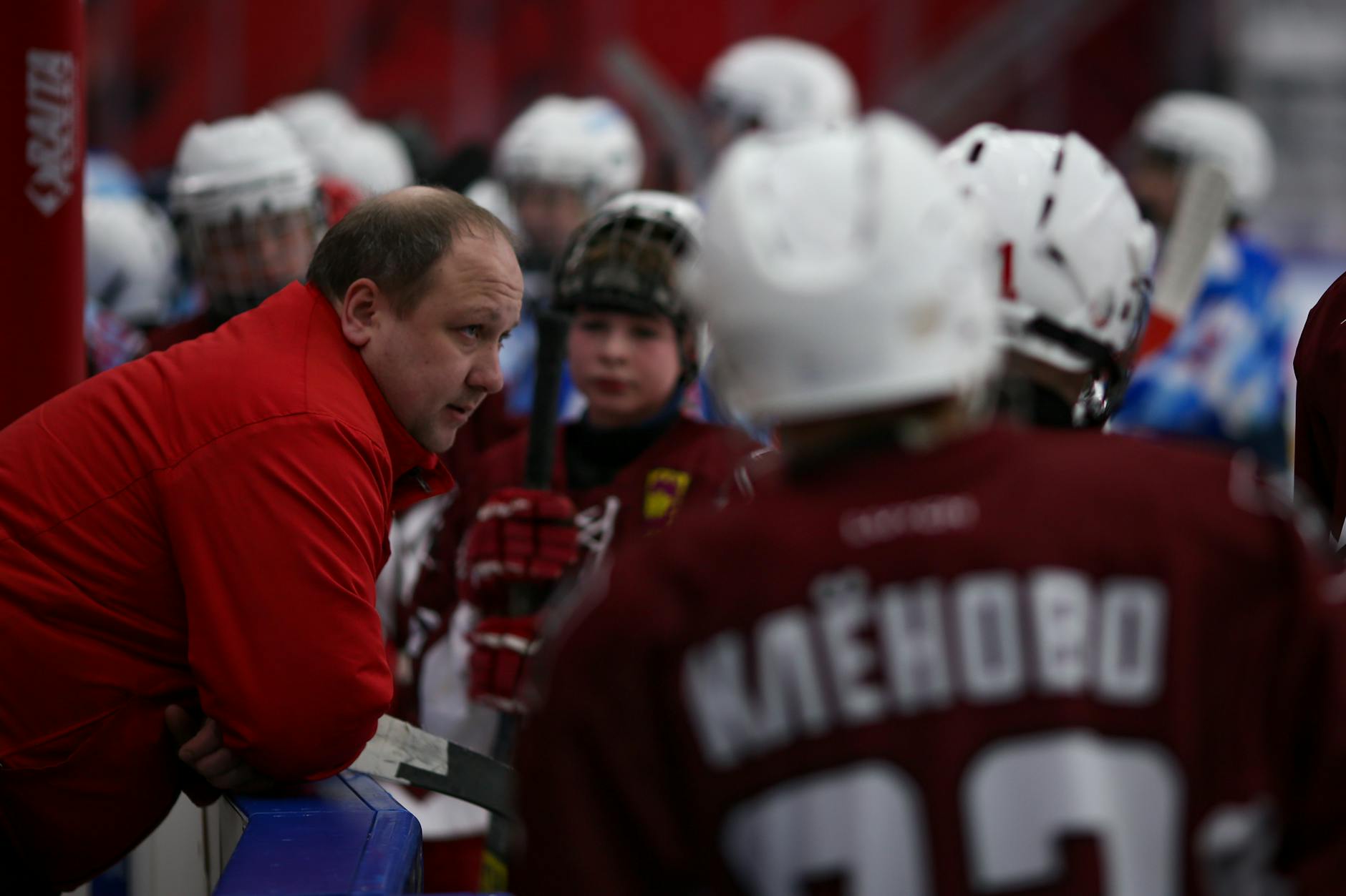 Male trainer talking with children in hockey uniform at ice rink during break of hockey game - active listening in relationships
