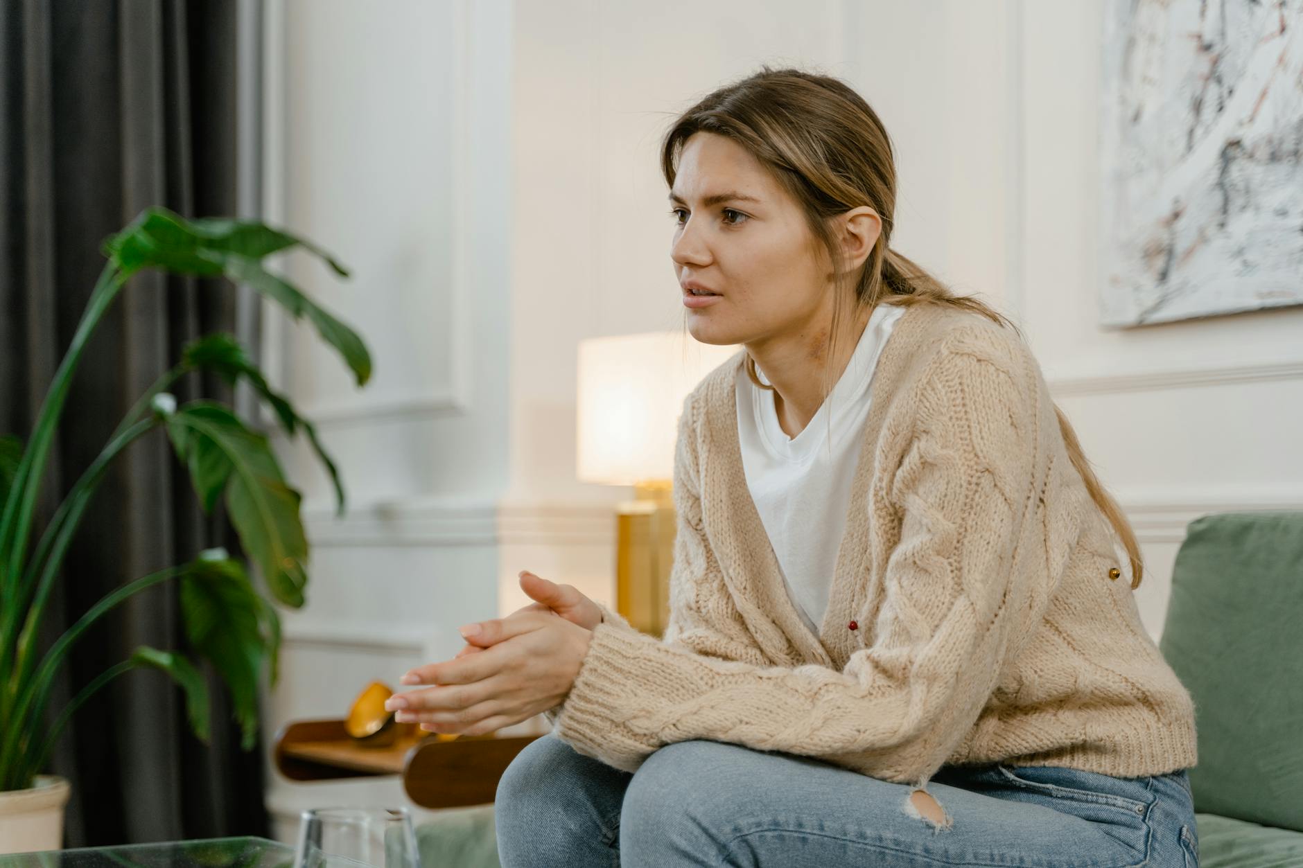 Woman in a casual setting appears deep in thought while sitting on a couch at home. - anxiety and depression treatment