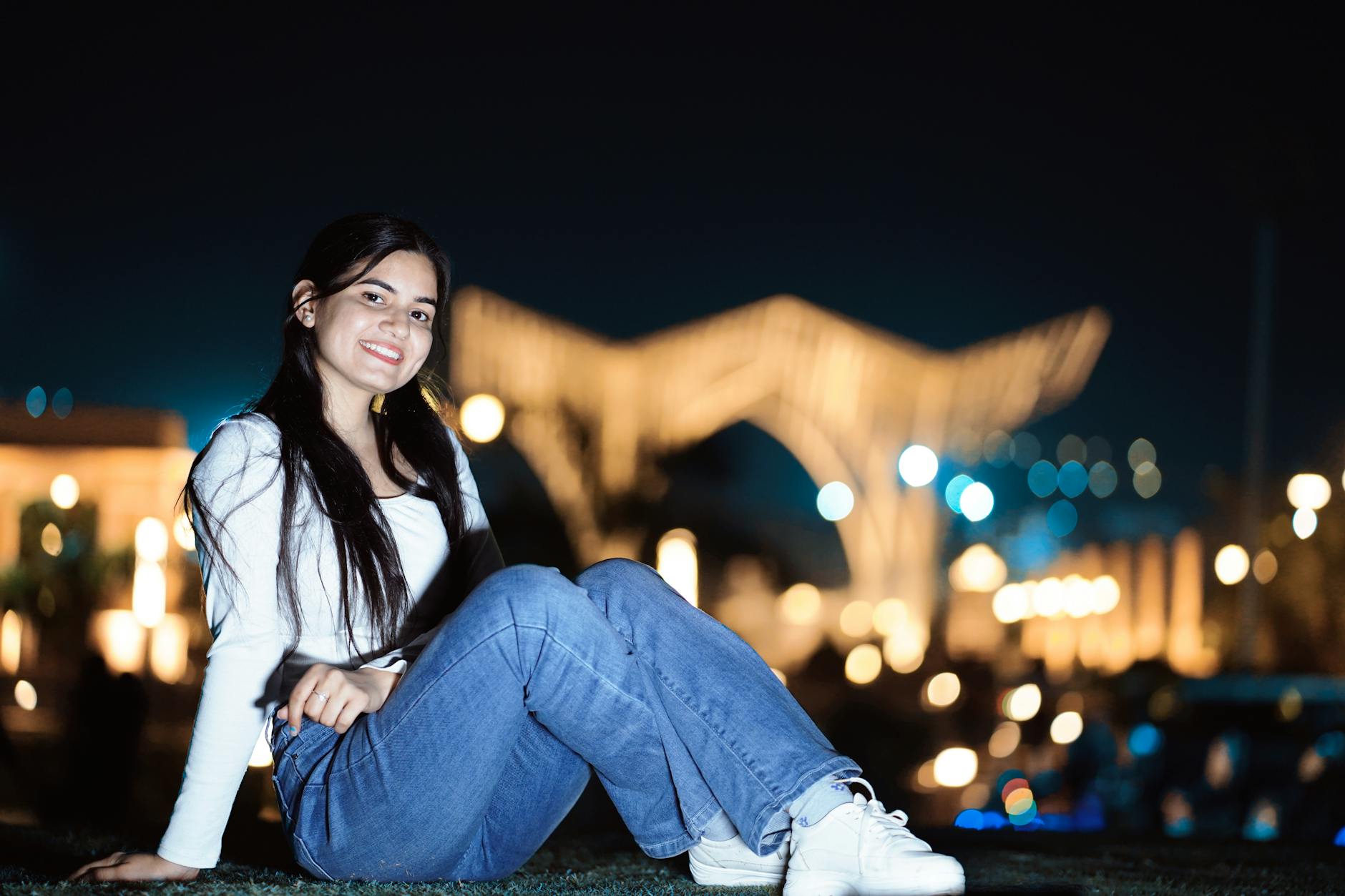 Young woman posing with a smile in an outdoor nighttime setting with blurred lights. - how to apologize to boyfriend