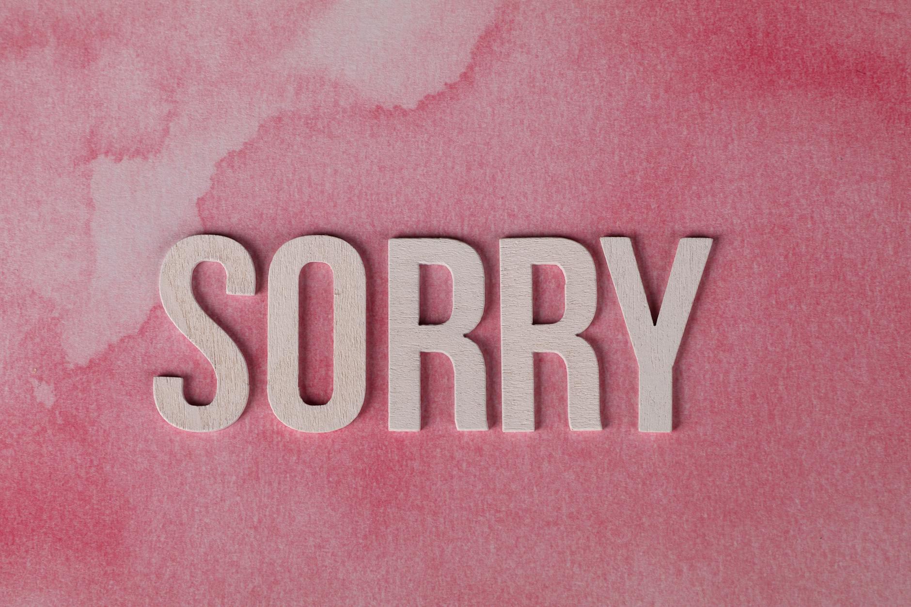 The word 'Sorry' displayed on a pink watercolor textured background, expressing an apology. - how to apologize effectively
