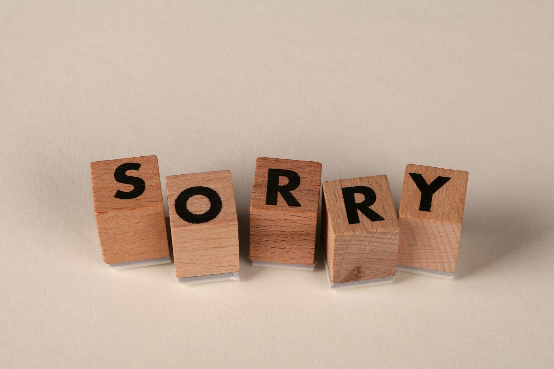 Wooden blocks arranged to spell 'Sorry' on a light, neutral background. - apologize to a friend