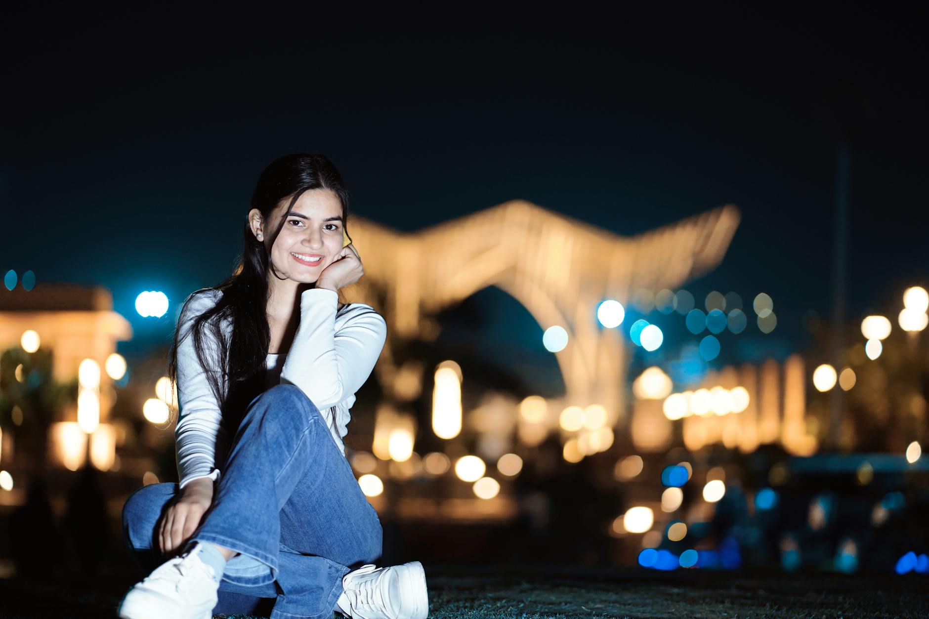 Portrait of a young woman smiling outdoors at night with city lights in the background. - how to apologize professionally