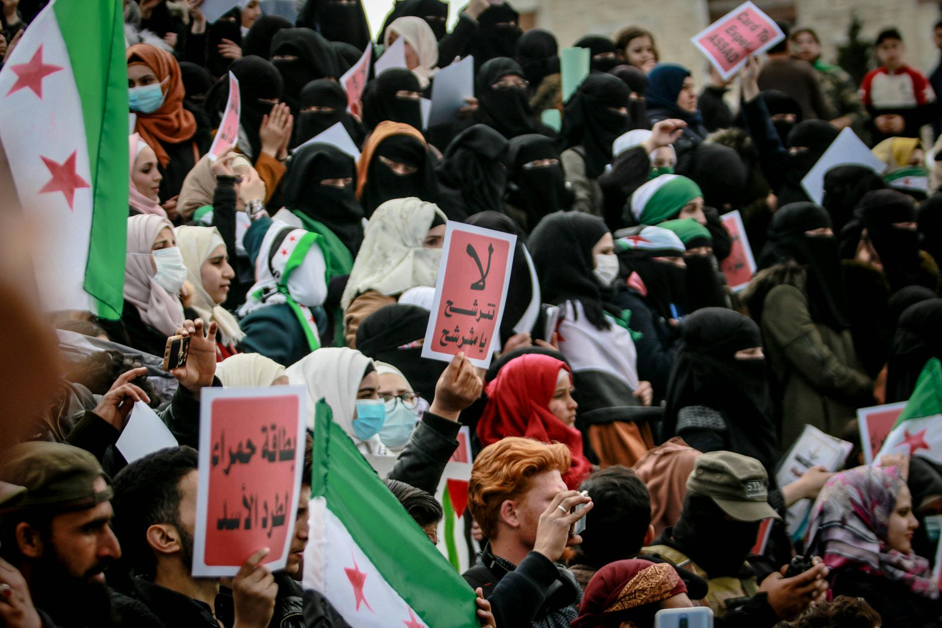 A vibrant protest in Syria with people holding flags and signs, demonstrating activism. - assertive communication in conflict