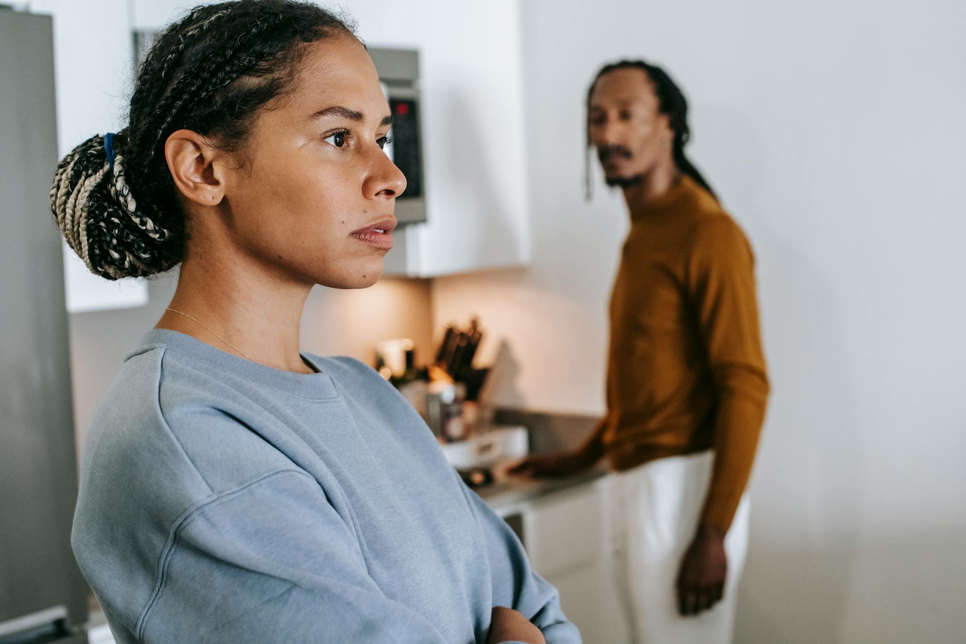 A serious young couple having a discussion in a modern kitchen setting, focusing on communication and emotions. - cbt for winter negative self-talk