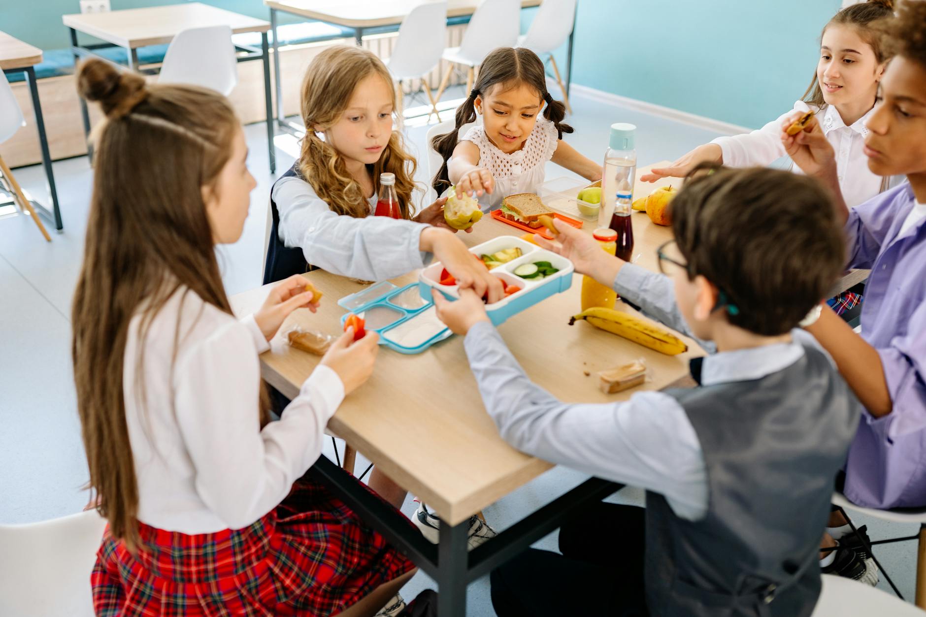 Group of diverse children having lunch in a school canteen, sharing and enjoying healthy snacks. - child social emotional development break