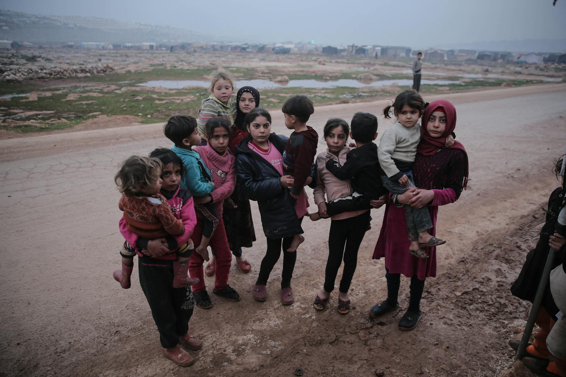 A group of children standing on an unpaved road in Idlib, Syria, showcasing resilience. - children's empathy winter service