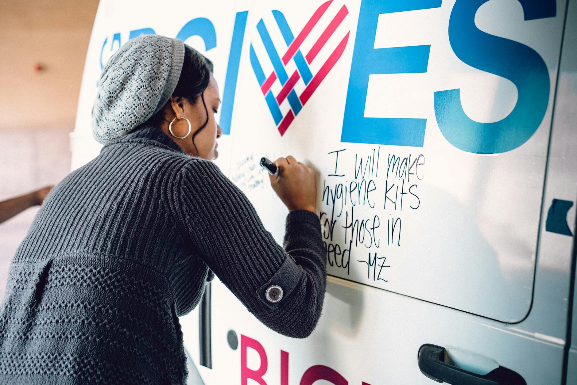 A black woman writes an inspirational note on a charity van, participating in a community event. - children's empathy winter service
