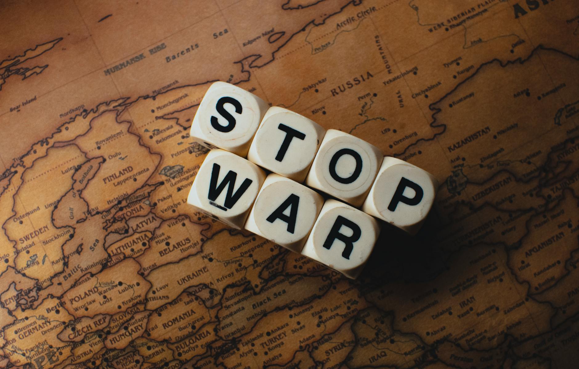 Dice with 'STOP WAR' on a vintage world map signifies peace. - conflict resolution definition