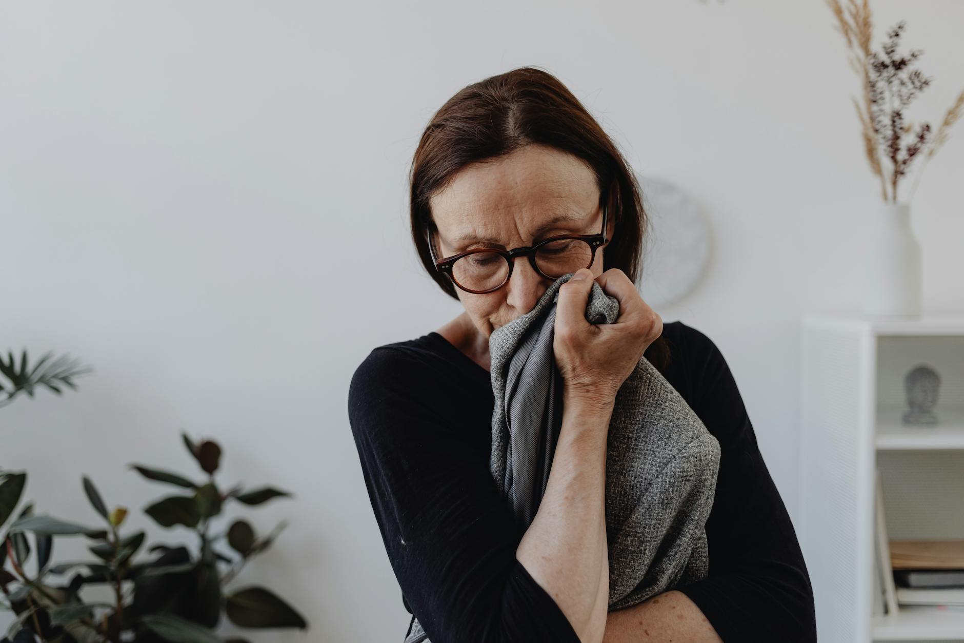 A middle-aged woman grieves while holding a cloth in an indoor setting. - coping with grief in winter