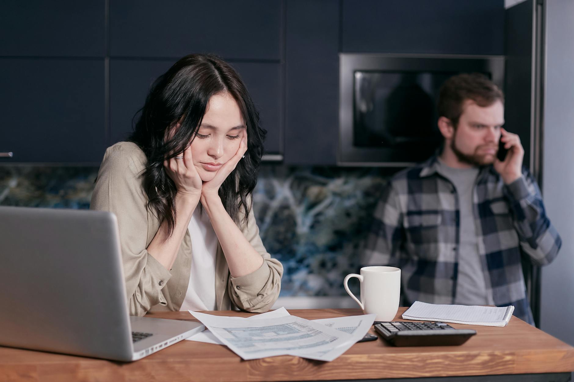 Couple dealing with financial stress at home, surrounded by bills and a laptop. - couples financial stress communication