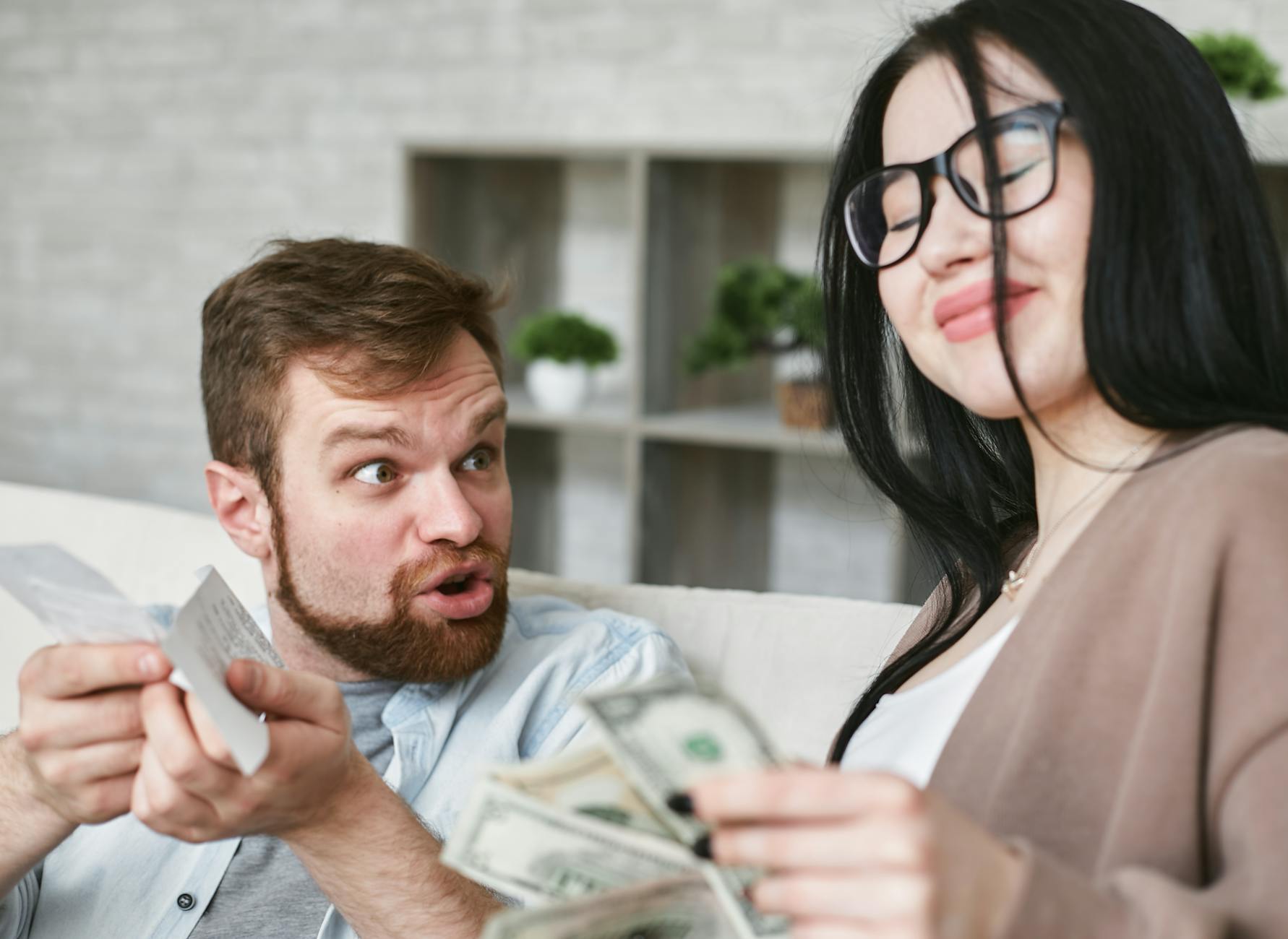 Interracial couple arguing over bills and cash at home. - couples financial stress communication