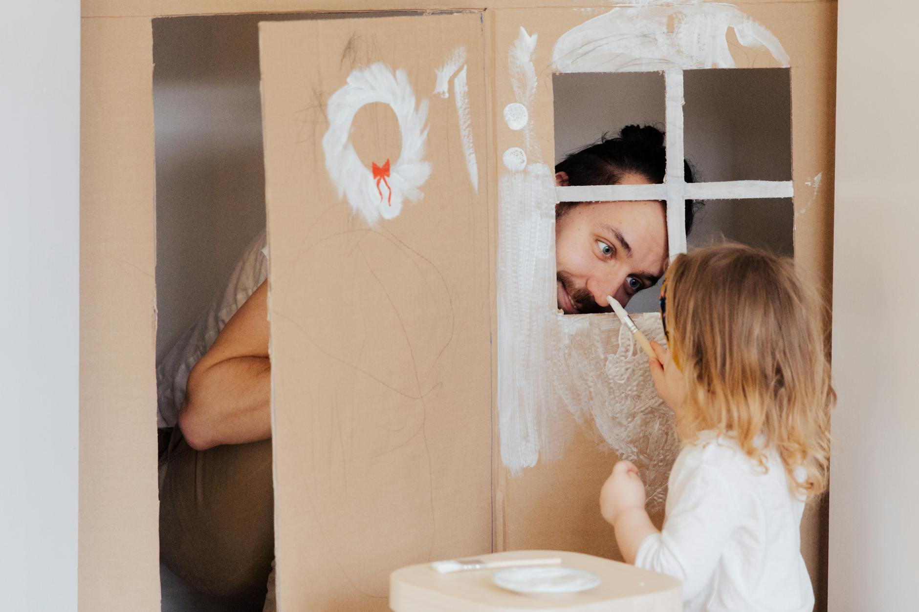 Father and daughter enjoying creative bonding by painting a cardboard playhouse indoors. - creative indoor play snowy days