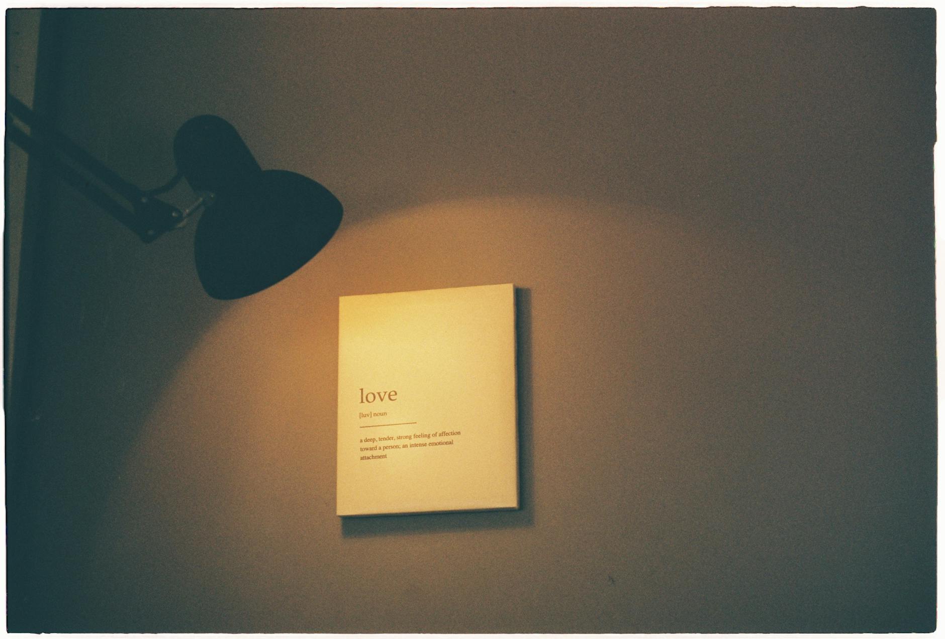 A warm-lit room showcasing a board with the definition of love illuminated by a lamp. - emotional validation definition