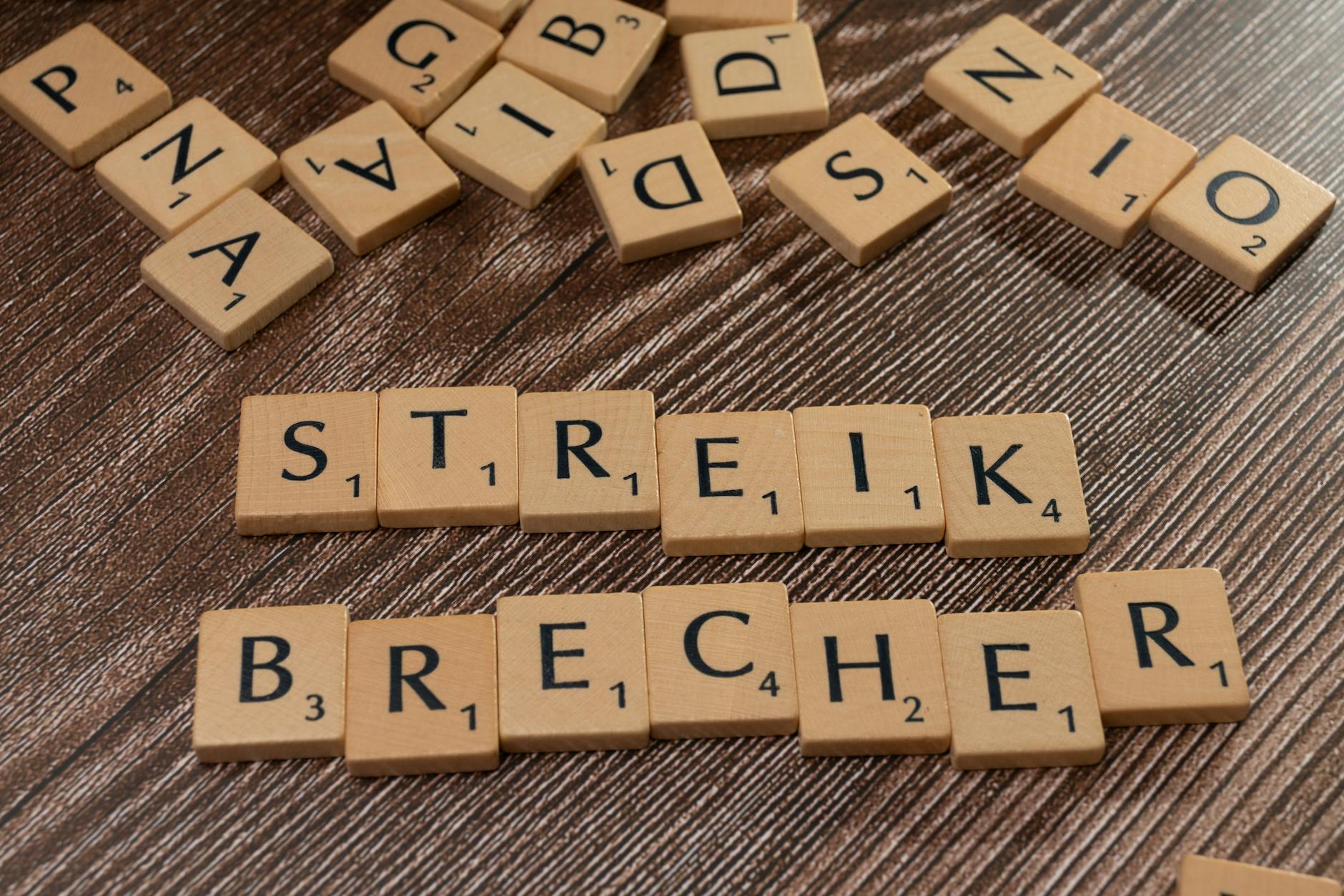 Wooden Scrabble tiles spelling 'Streik Brecher' on a wooden surface. - family conflict resolution strategies
