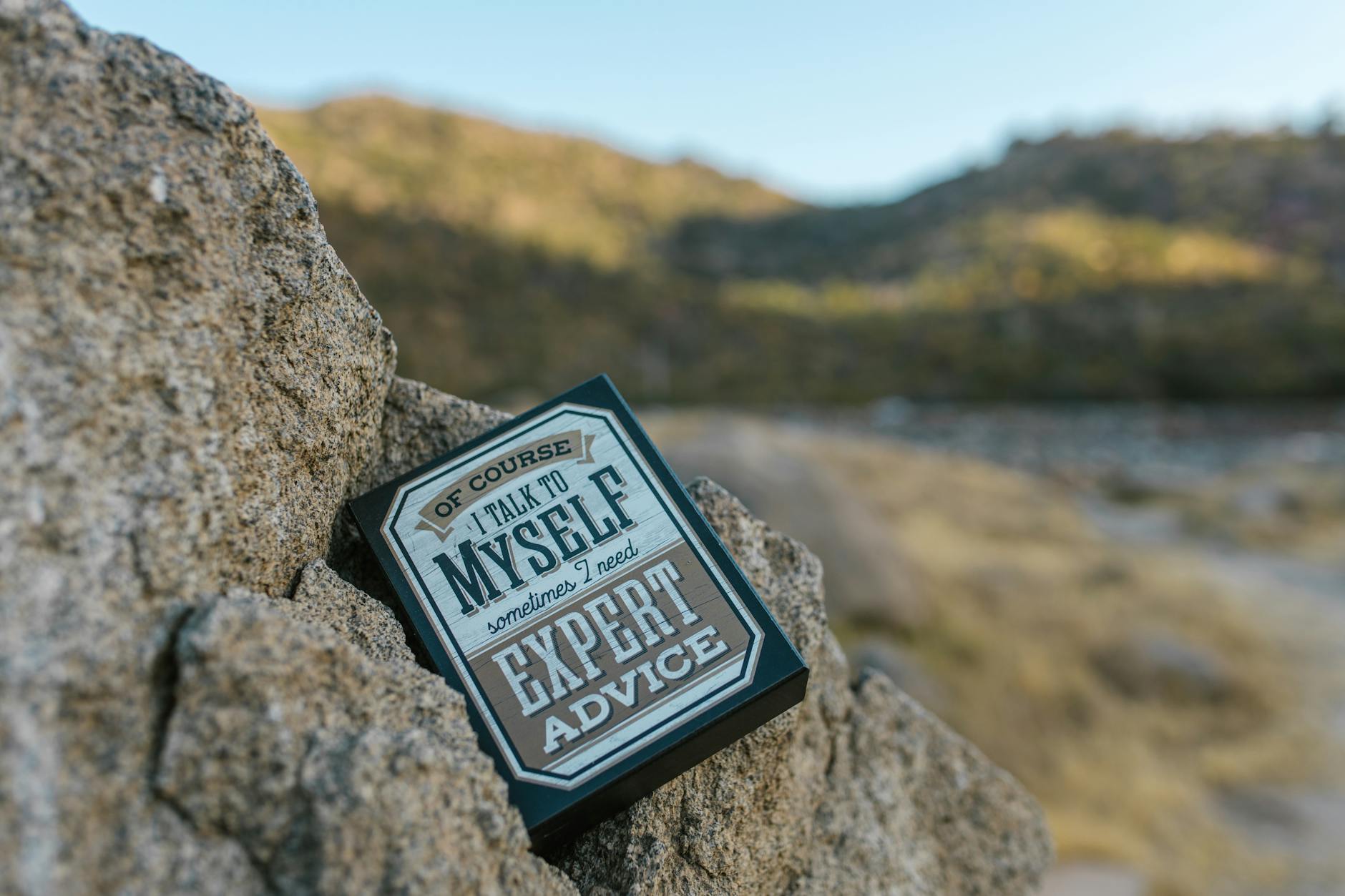 Close-up of a humorous motivational sign placed on rocks in an outdoor setting. - funny advice for newlyweds