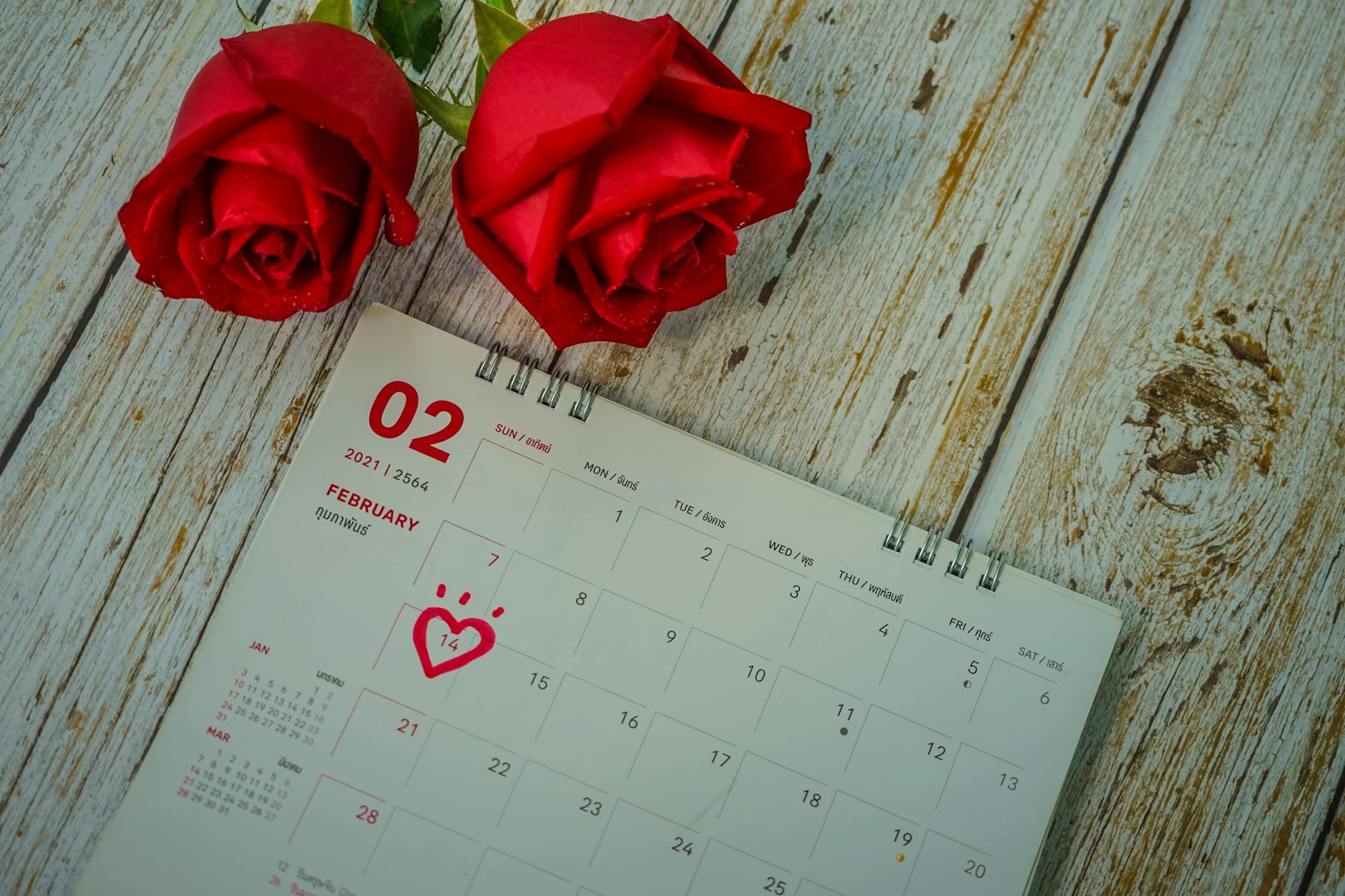 Red roses and a February calendar highlight Valentine's Day with marked date. - at home date ideas february