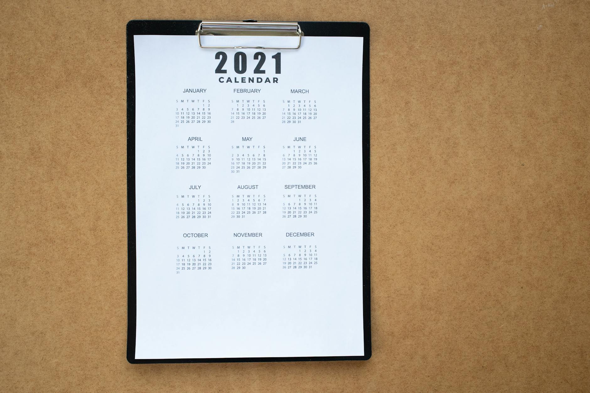 A 2021 calendar clipped to a black clipboard on a brown surface. Ideal for planning or scheduling visuals. - at home date ideas february