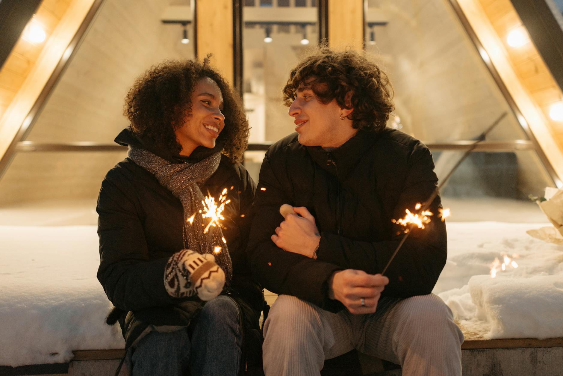 A couple enjoying a romantic winter evening outdoors, sharing sparklers and smiles. - intimate winter date ideas