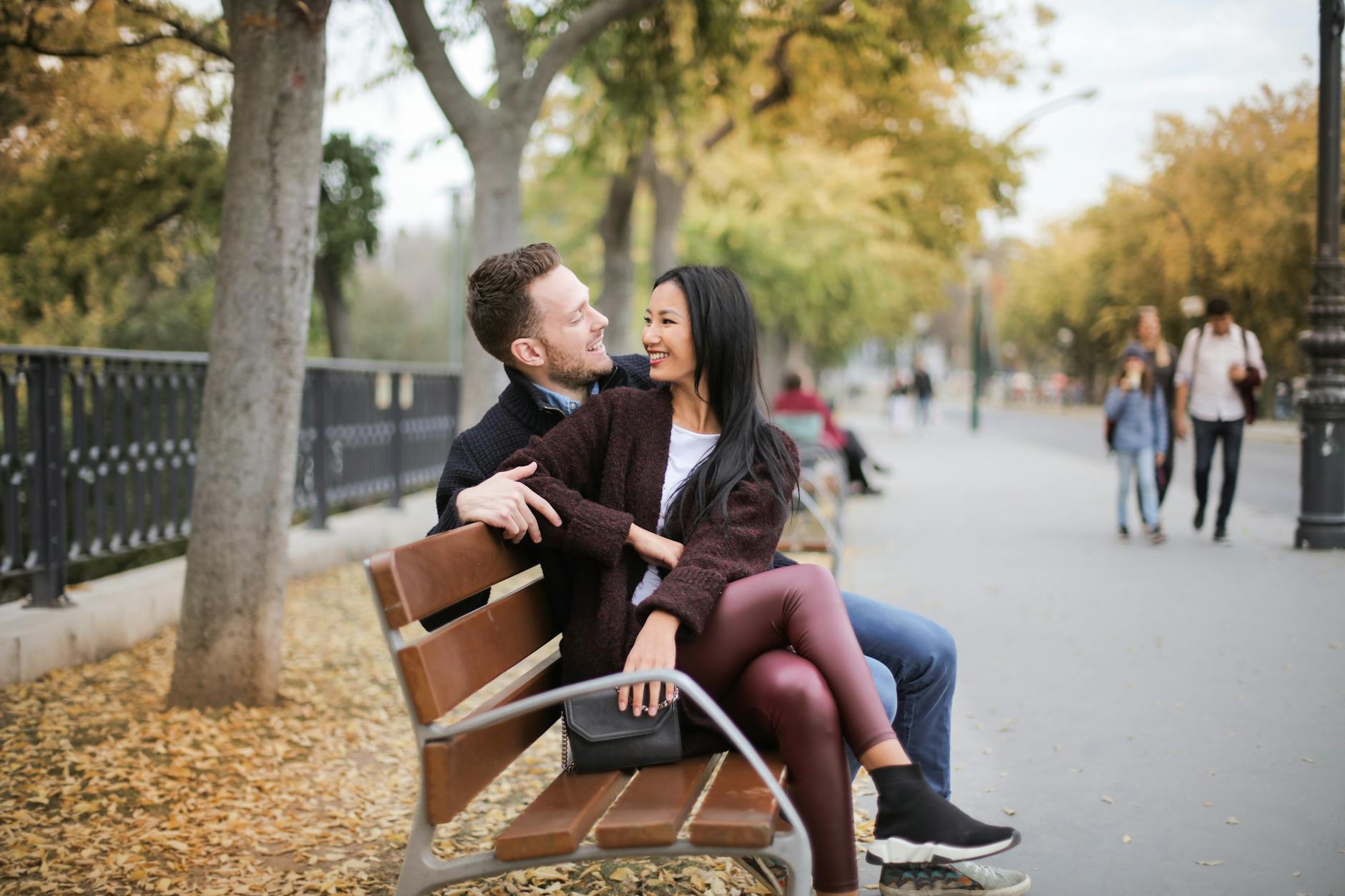 Happy couple sitting on a bench in a park during fall, sharing a joyful moment together. - introvert dating advice